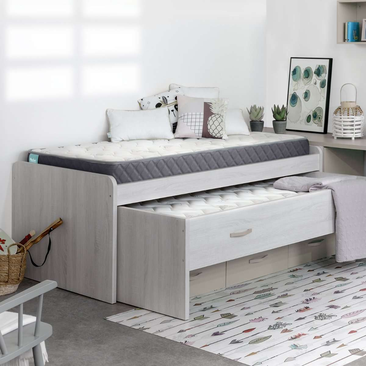 Escena de dormitorio con cama sobre cama extraíble, alfombra y decoraciones.
