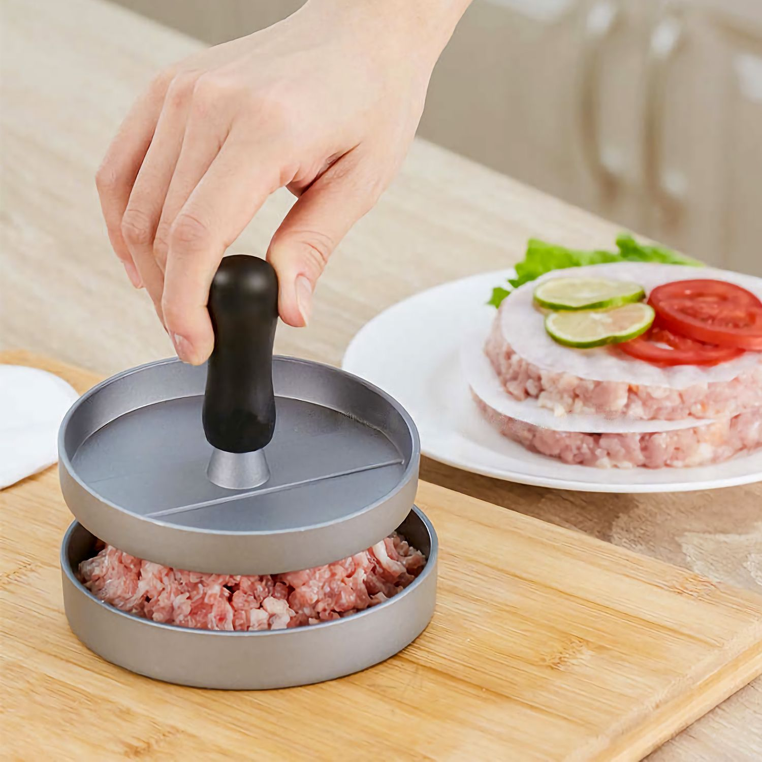 Eine Person, die eine Burgerpresse auf Hackfleisch auf einem Schneidebrett drückt.