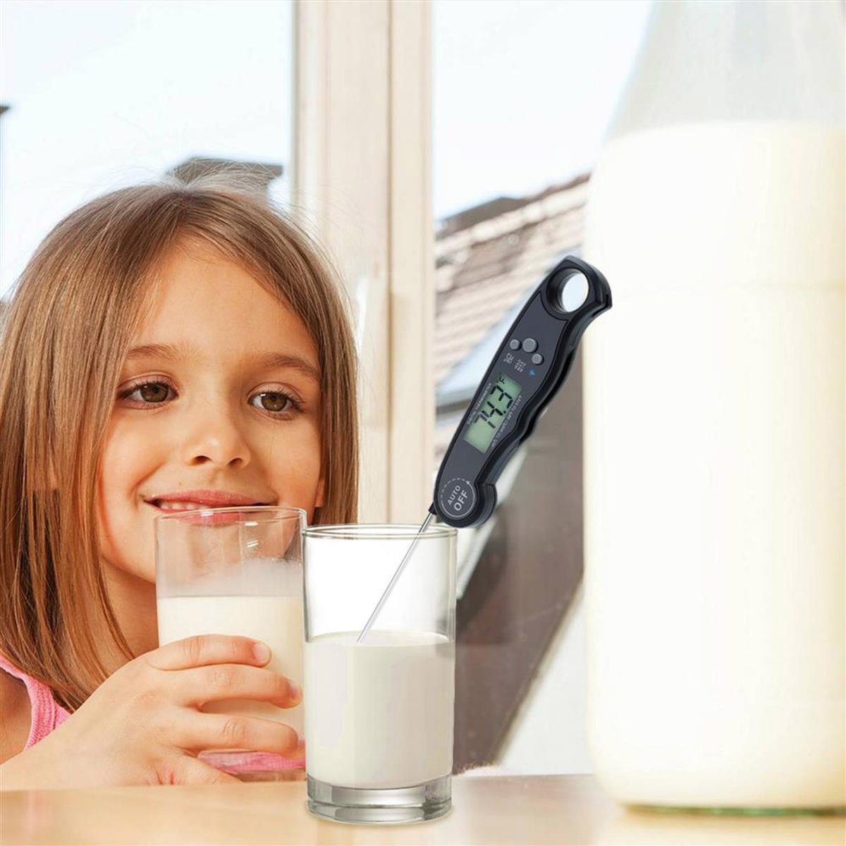 Mädchen hält ein Glas Milch, ein Thermometer in einem Glas Milch und eine Milchflasche.