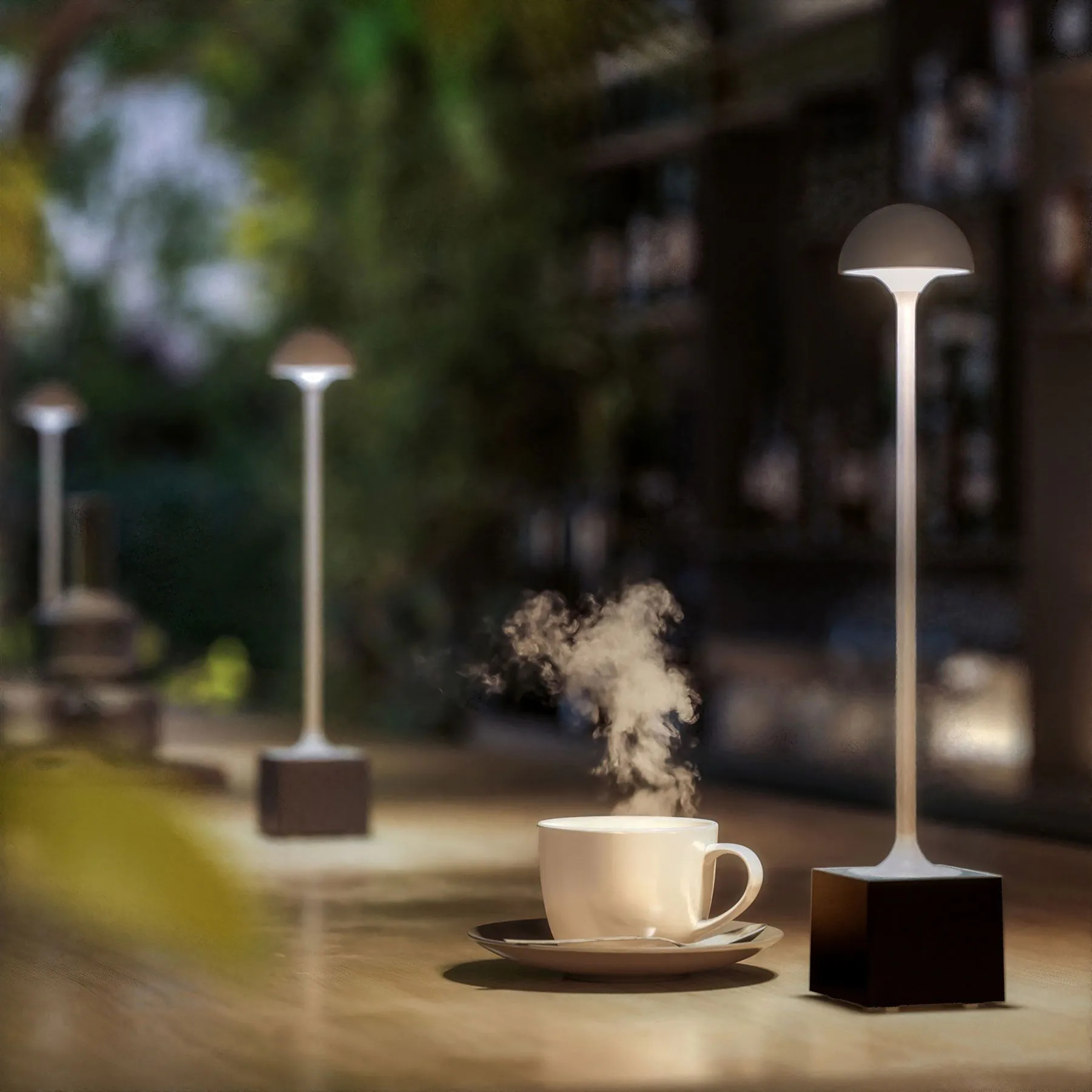 Filiżanka kawy z parą, trzy lampy zewnętrzne na barze. Ciemne otoczenie.