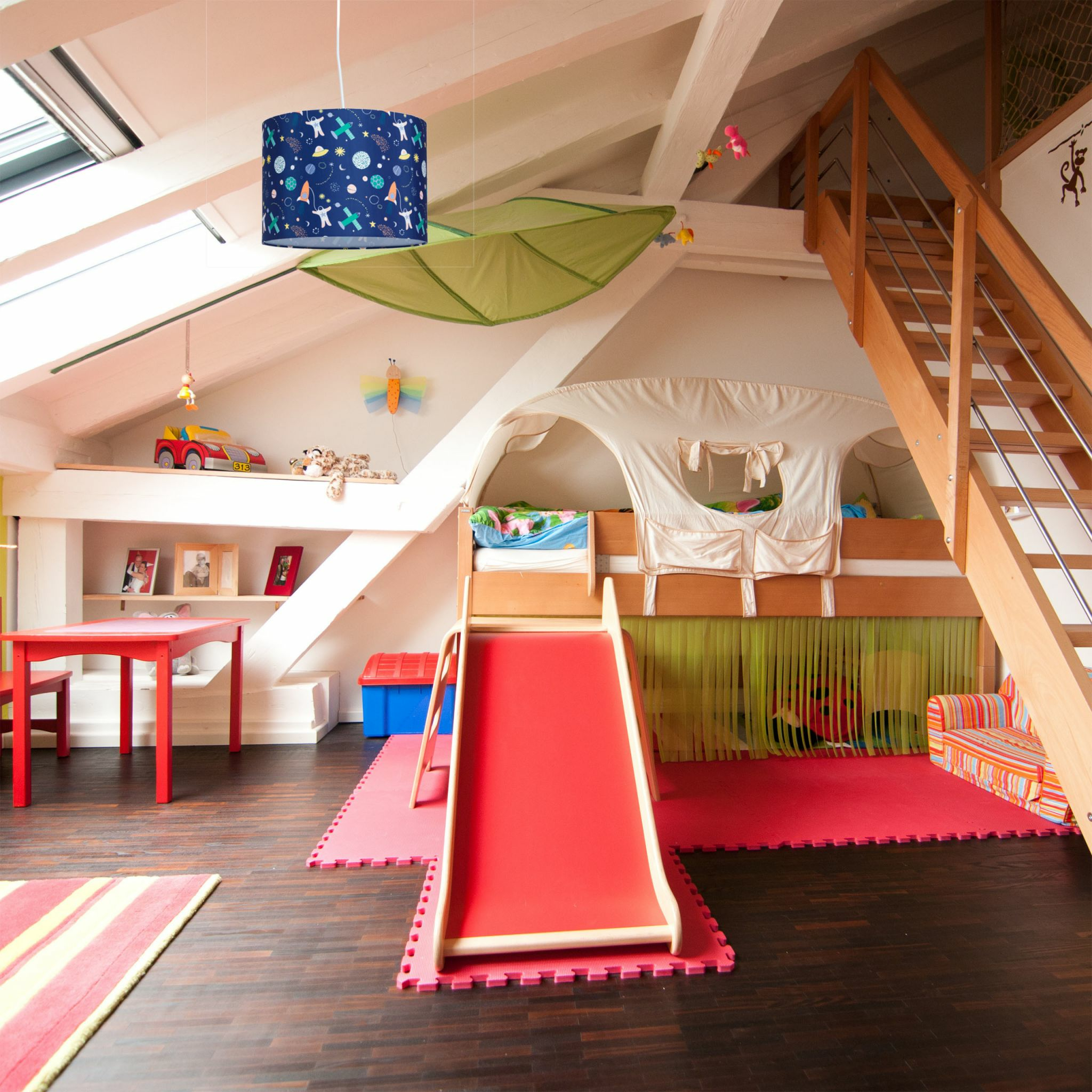 Ein farbenfrohes Kinderzimmer mit Rutsche, Spielbereich und Pendelleuchte.