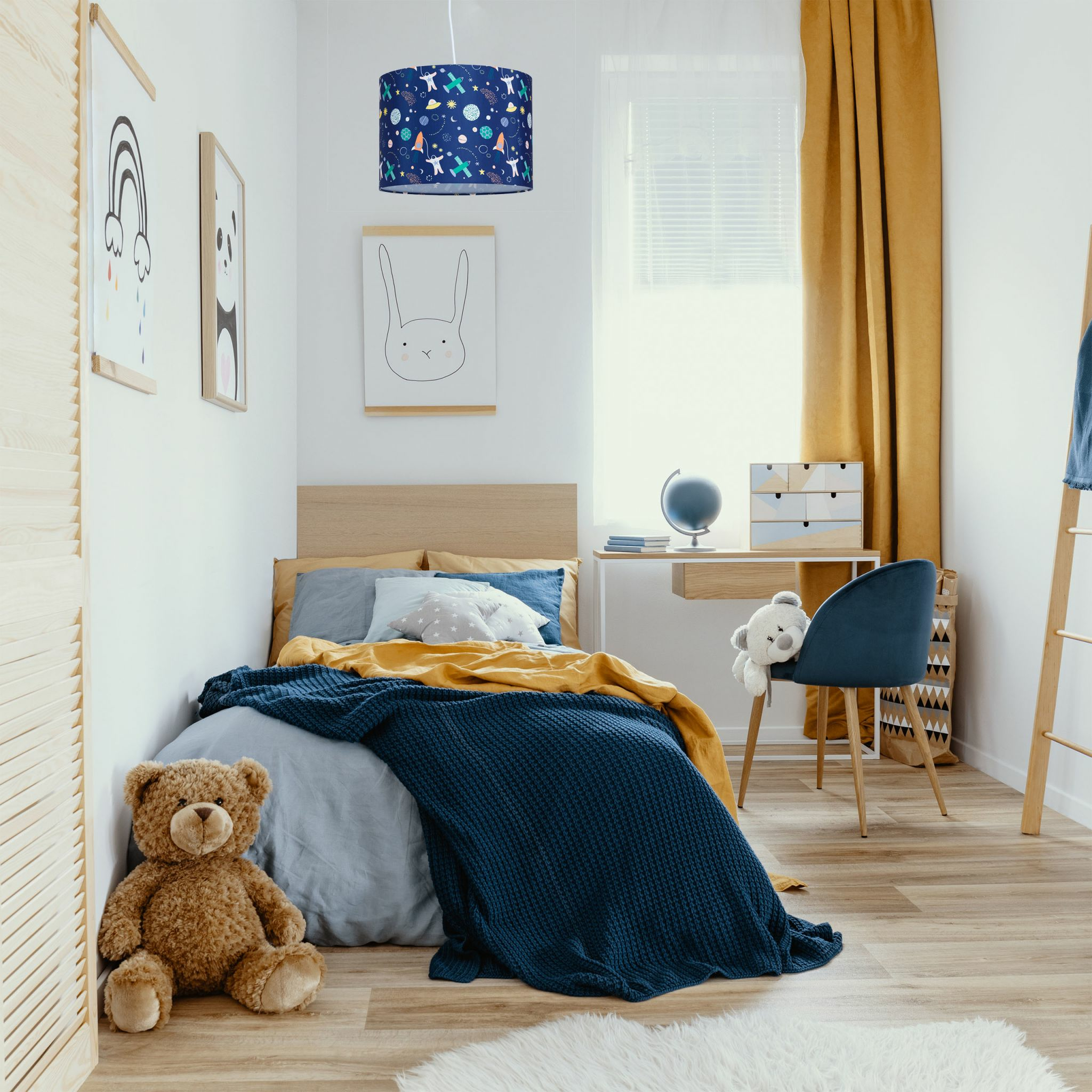 Schlafzimmer mit blauem, gemustertem Lampenschirm, Bett, Teddybär und Schreibtisch.