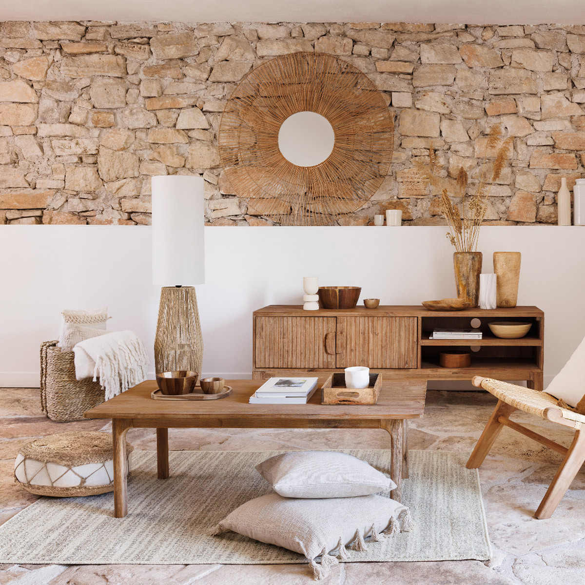 Un soggiorno con parete in pietra, mobili in legno, specchio e vari oggetti decorativi.