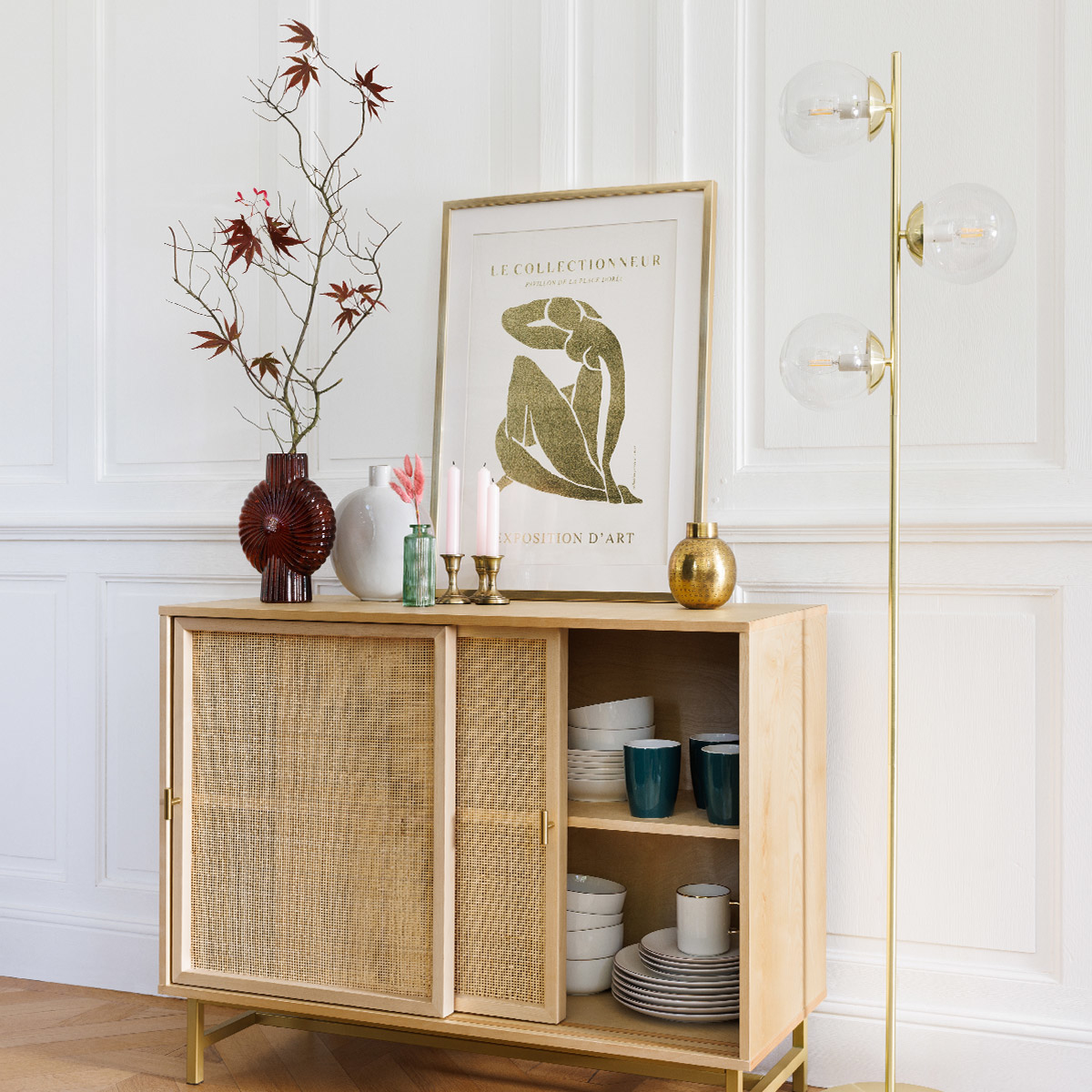 Un mobile con piano in legno, arte incorniciata e una lampada da terra con luci a globo.