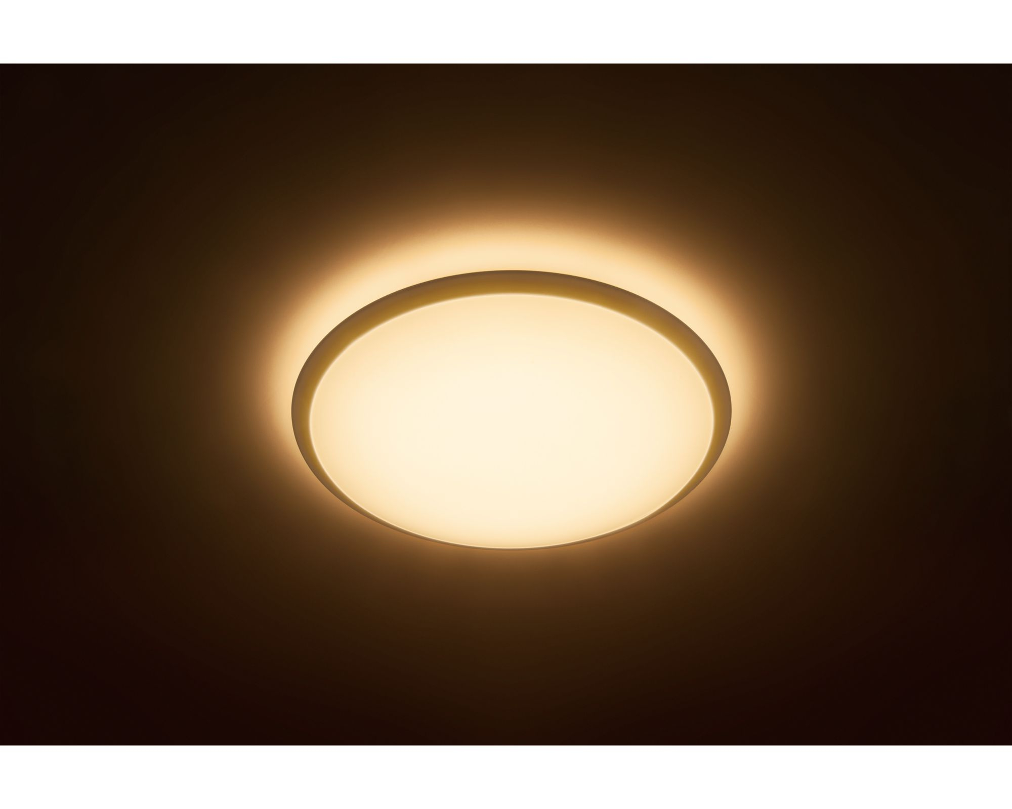 Una plafoniera rotonda che si illumina di una calda luce gialla in una stanza buia.