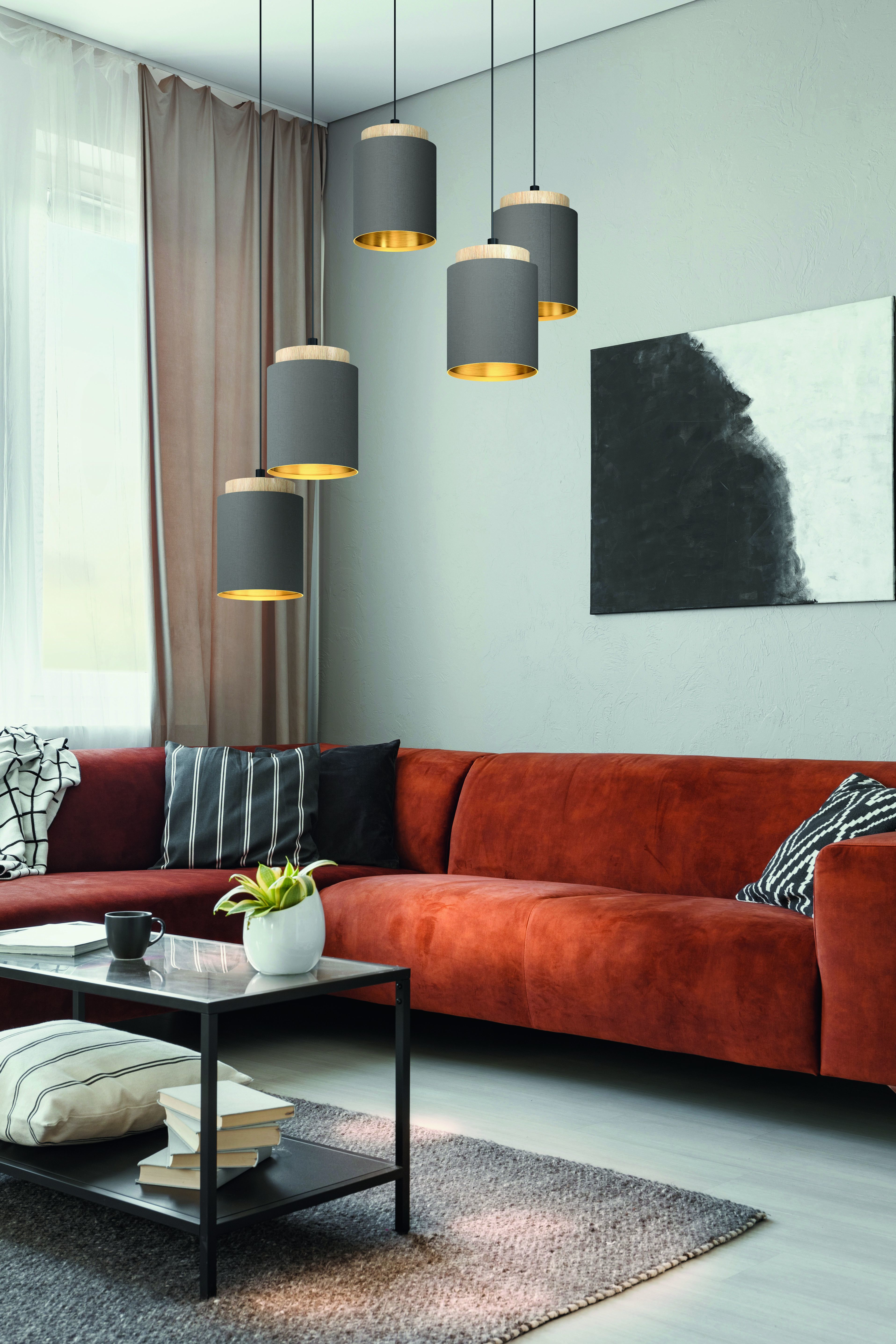 Wohnzimmer mit rotem Ecksofa, Hängelampen, Kunst und einem Couchtisch.