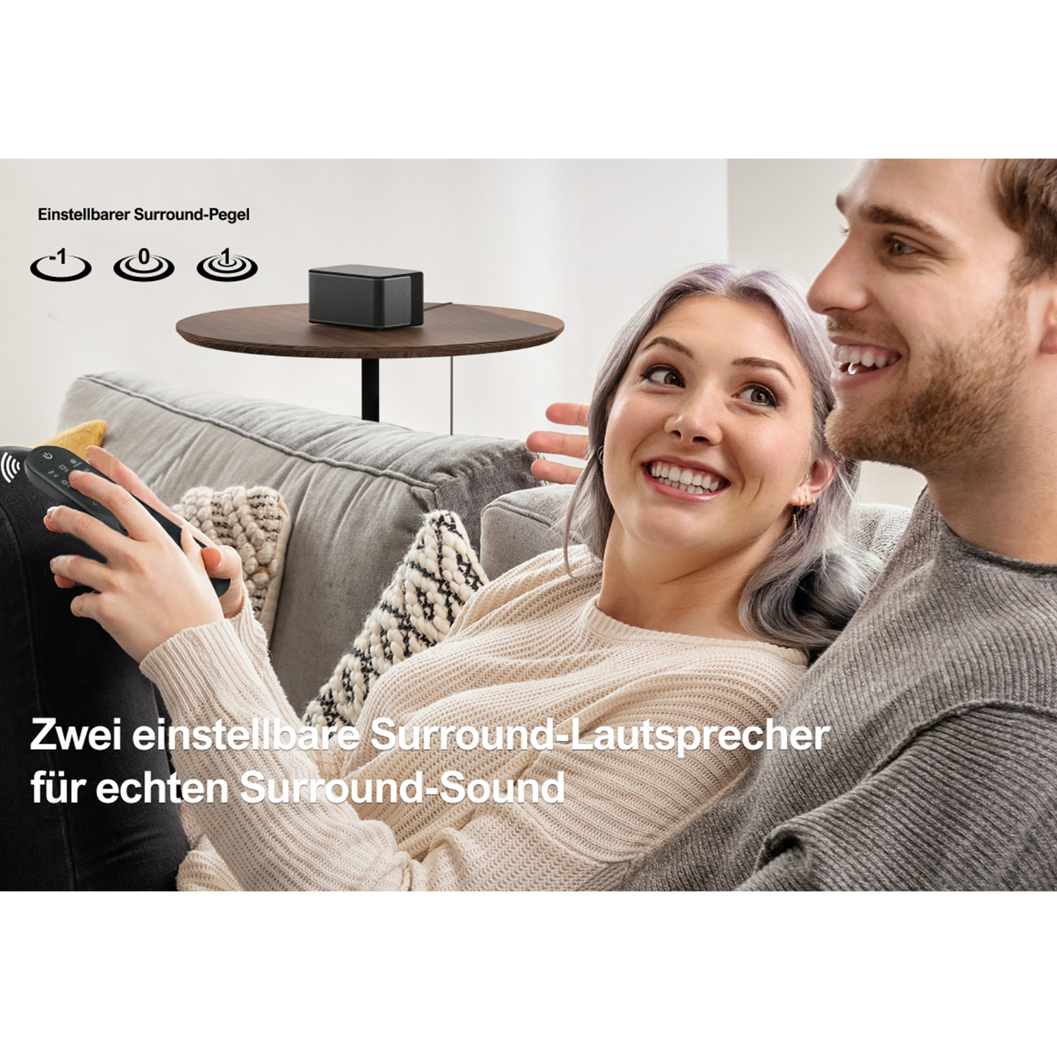 Ein Mann und eine Frau lächeln. Ein kleiner schwarzer Lautsprecher steht auf einem Tisch. Text: Surround-Sound.