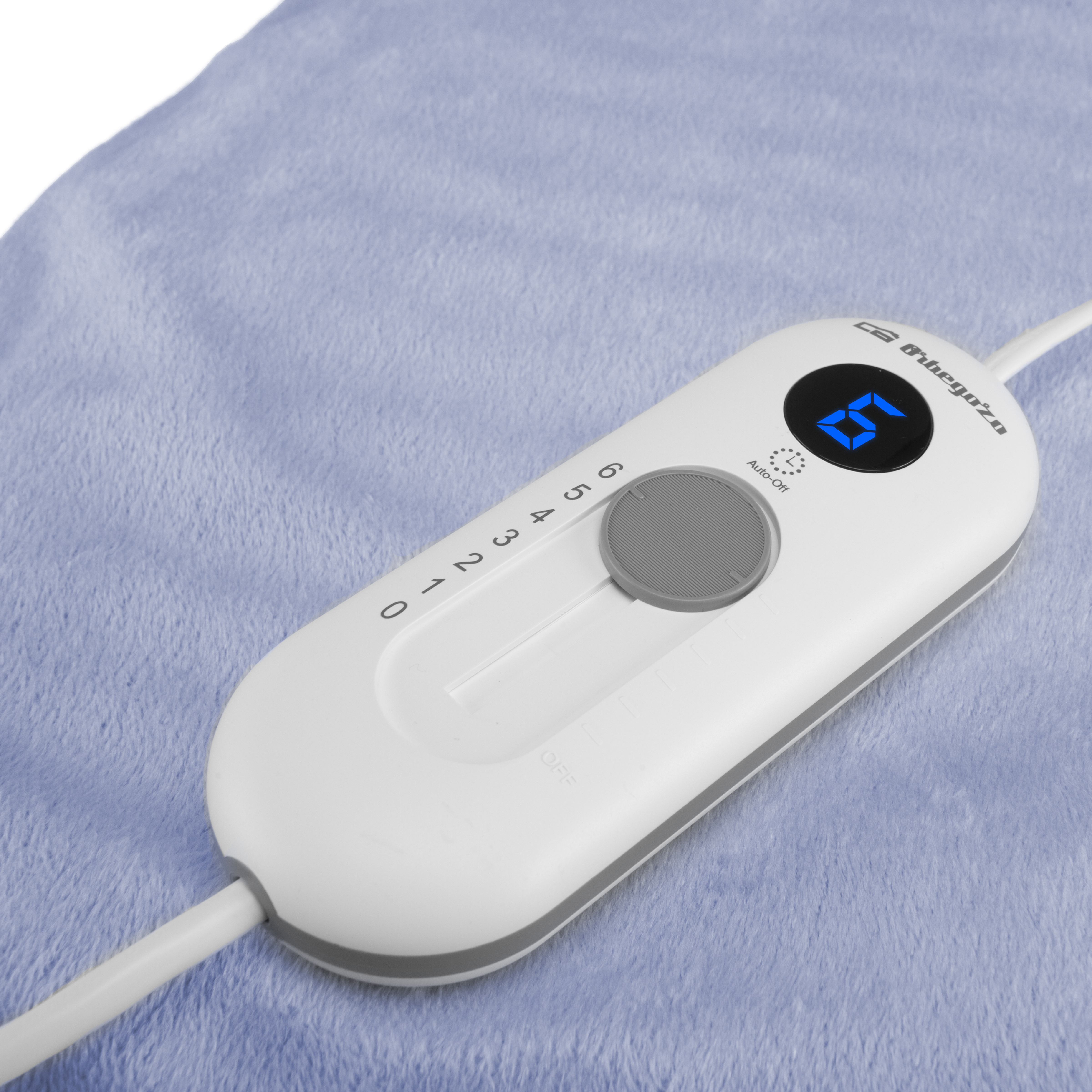 Controlador de almohadilla térmica, blanco, con un dial de 0-6 y una pantalla digital, sobre una superficie azul.