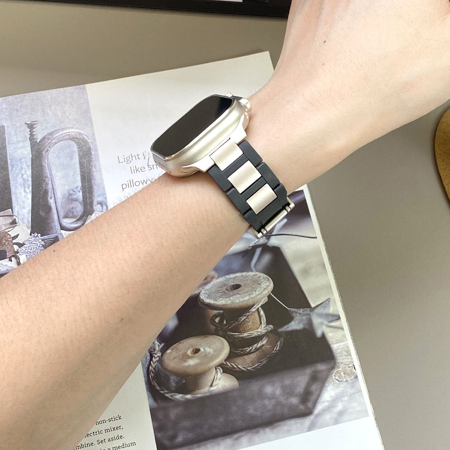 Handgelenk mit Smartwatch, zeigt ein schwarzes und goldenes Armband.