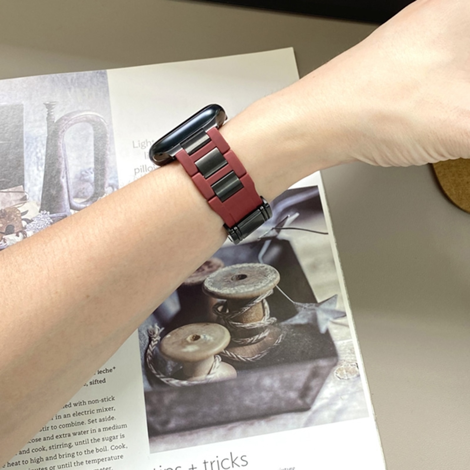 Das Handgelenk einer Person mit einer Apple Watch und einem rot-schwarzen Armband.