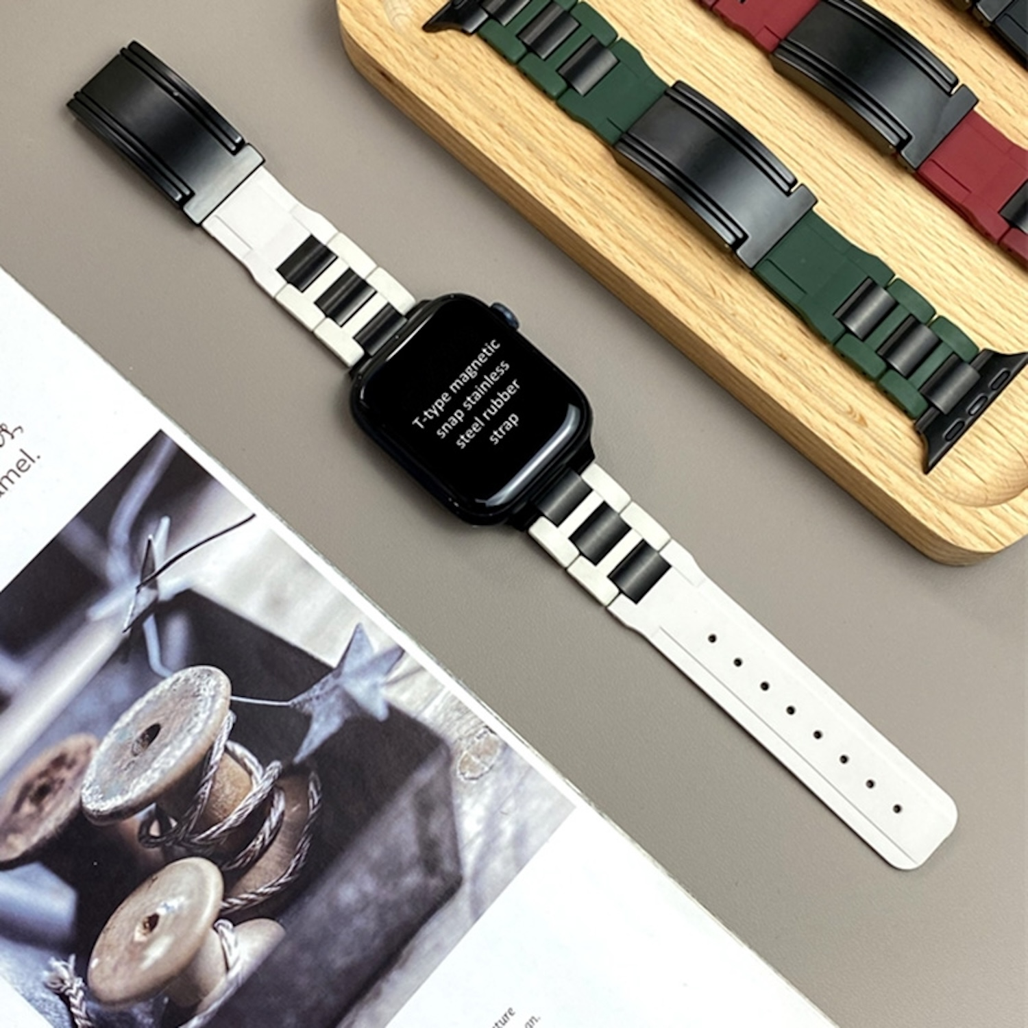 Ein weißes und schwarzes Uhrenarmband mit Magnetverschluss, das auf einem Holzbrett liegt.