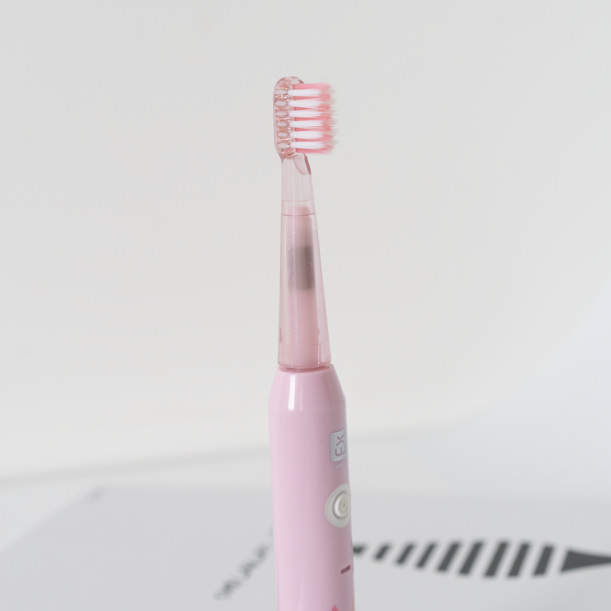 Primer plano de un cepillo de dientes eléctrico rosa sobre un fondo blanco.