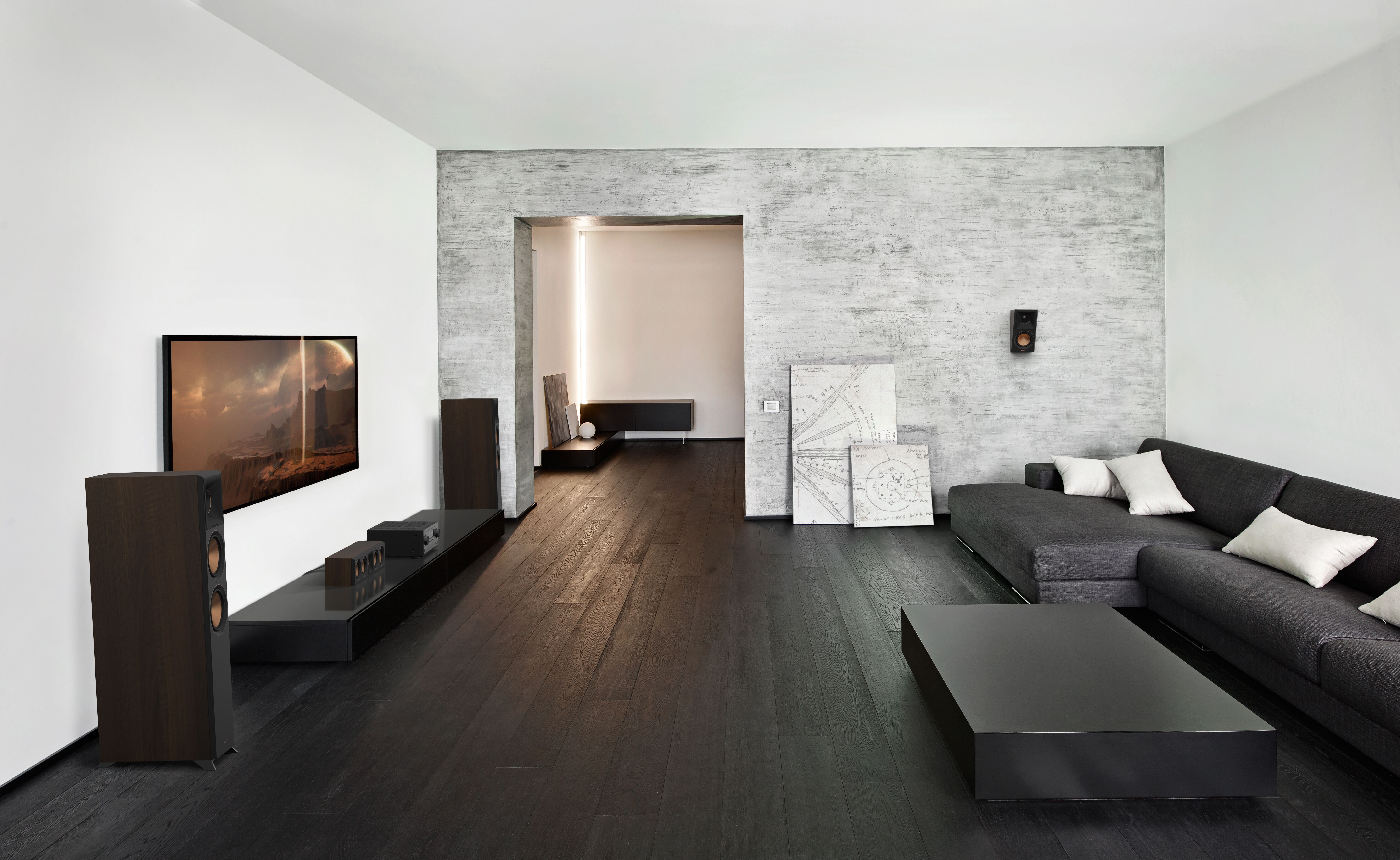 Modernes Wohnzimmer mit dunklem Holzboden, grauem Sofa und Fernseher an der Wand; neutrale Töne.