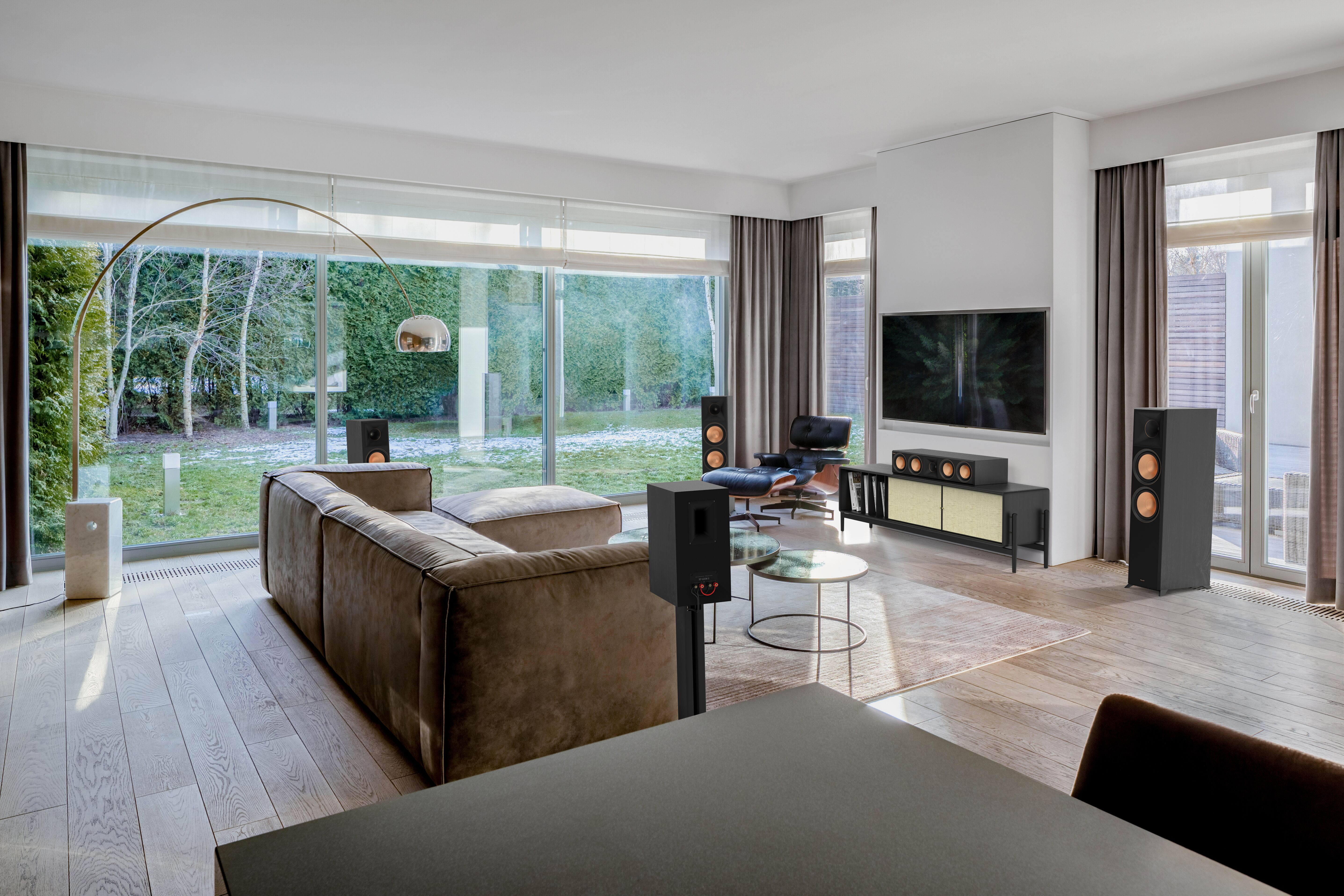 Woonkamer met bruine bank, speakers en tv.