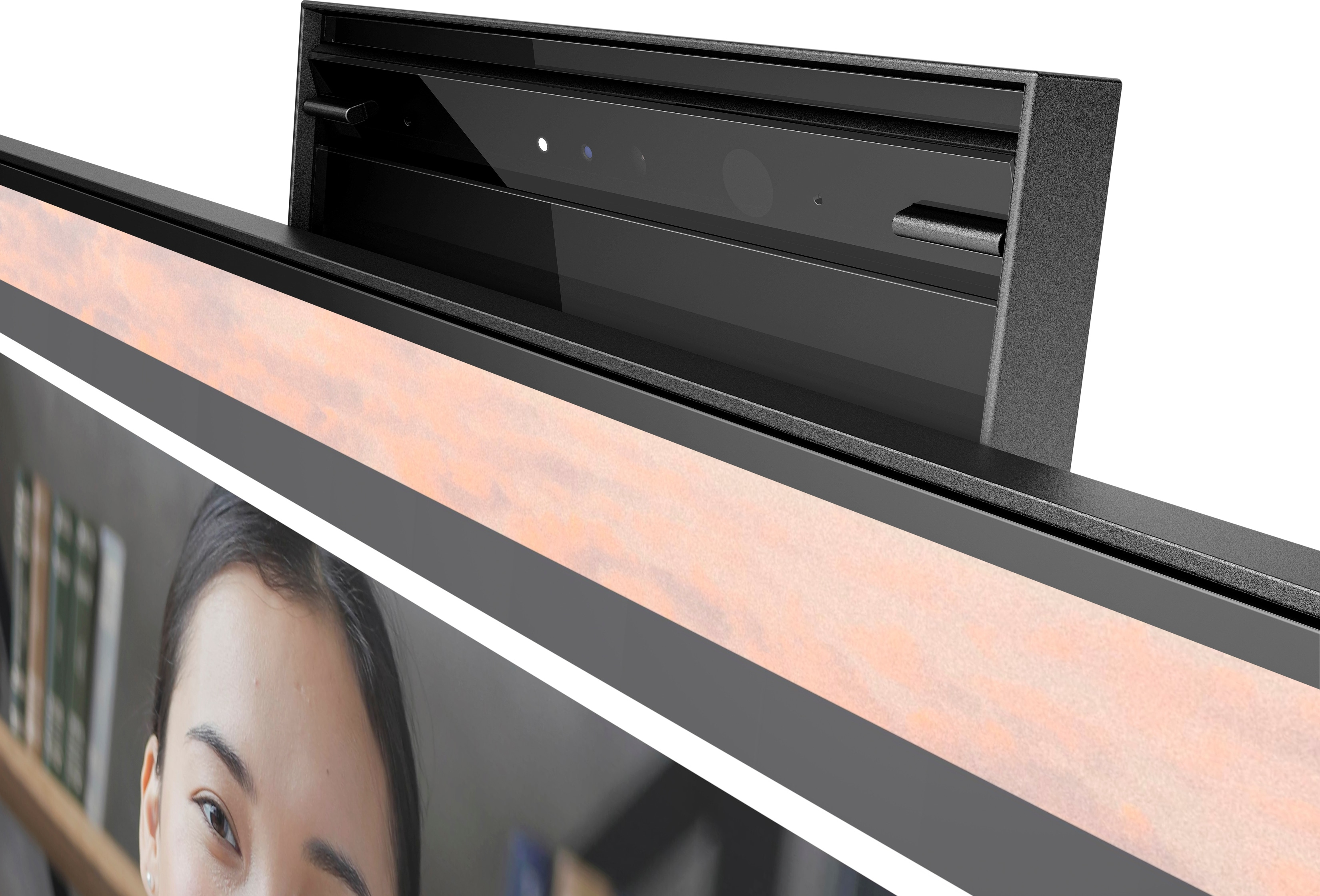 Close-up of a monitor with a webcam and light. A woman's face is partially visible below.