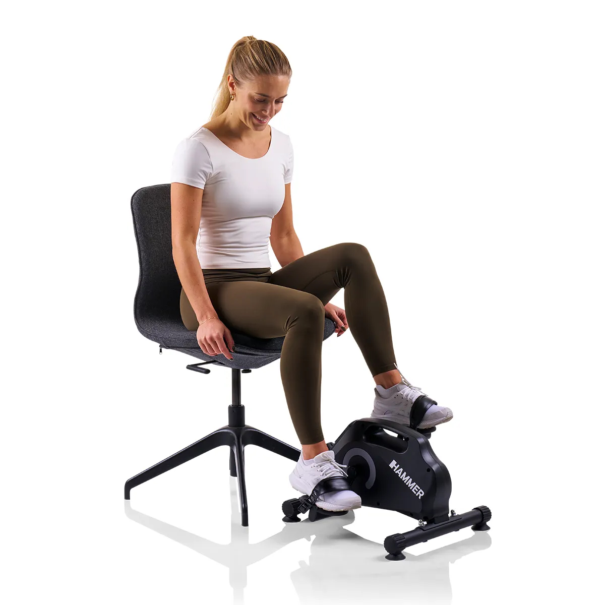 Eine Frau auf einem schwarzen stationären Trainingsfahrrad auf weißem Hintergrund.
