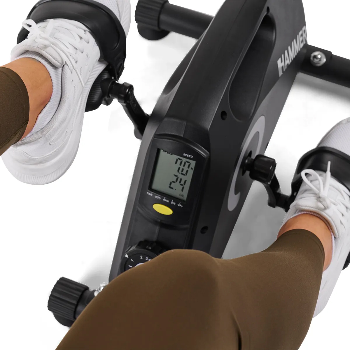 Beine und Füße einer Person auf einem Heimtrainer, mit digitaler Anzeige von Geschwindigkeit und Kalorien.