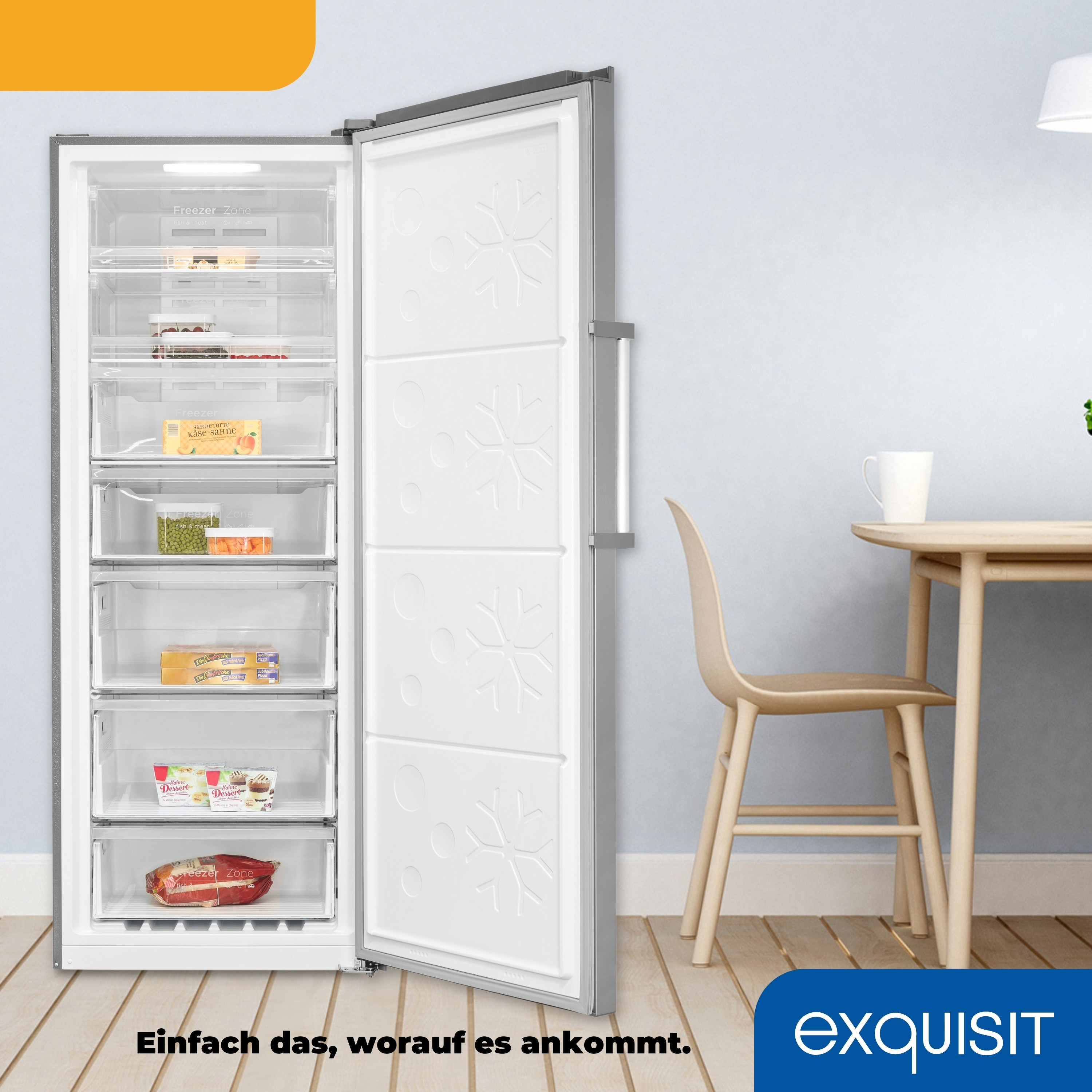 Offener weißer Kühlschrank mit Schubladen, etwas Essen darin. Holztisch und Stuhl im Hintergrund.