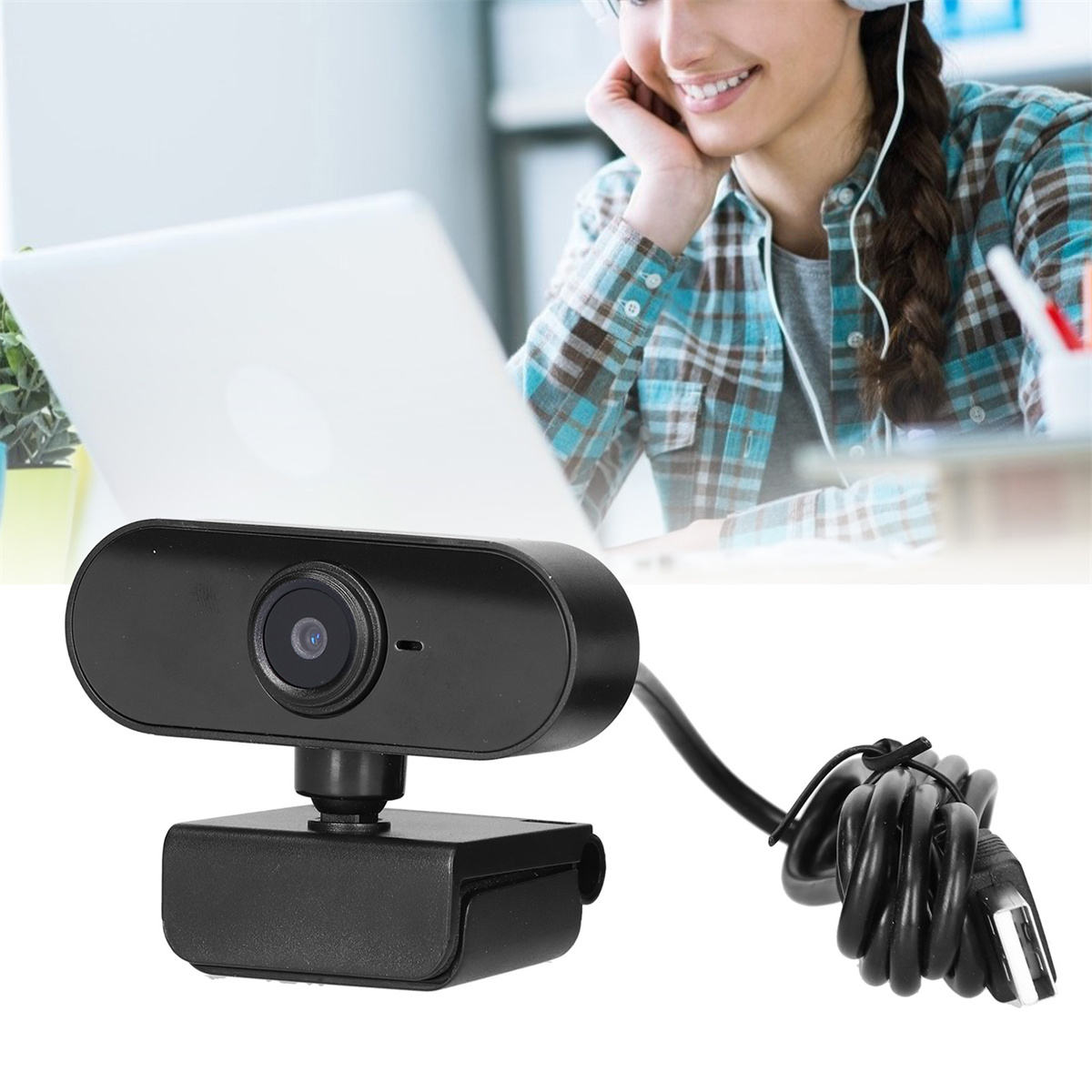 Schwarze Webcam, im Hintergrund eine Person, die einen Laptop benutzt. Ein schwarzes Kabel ist mit der Webcam verbunden.
