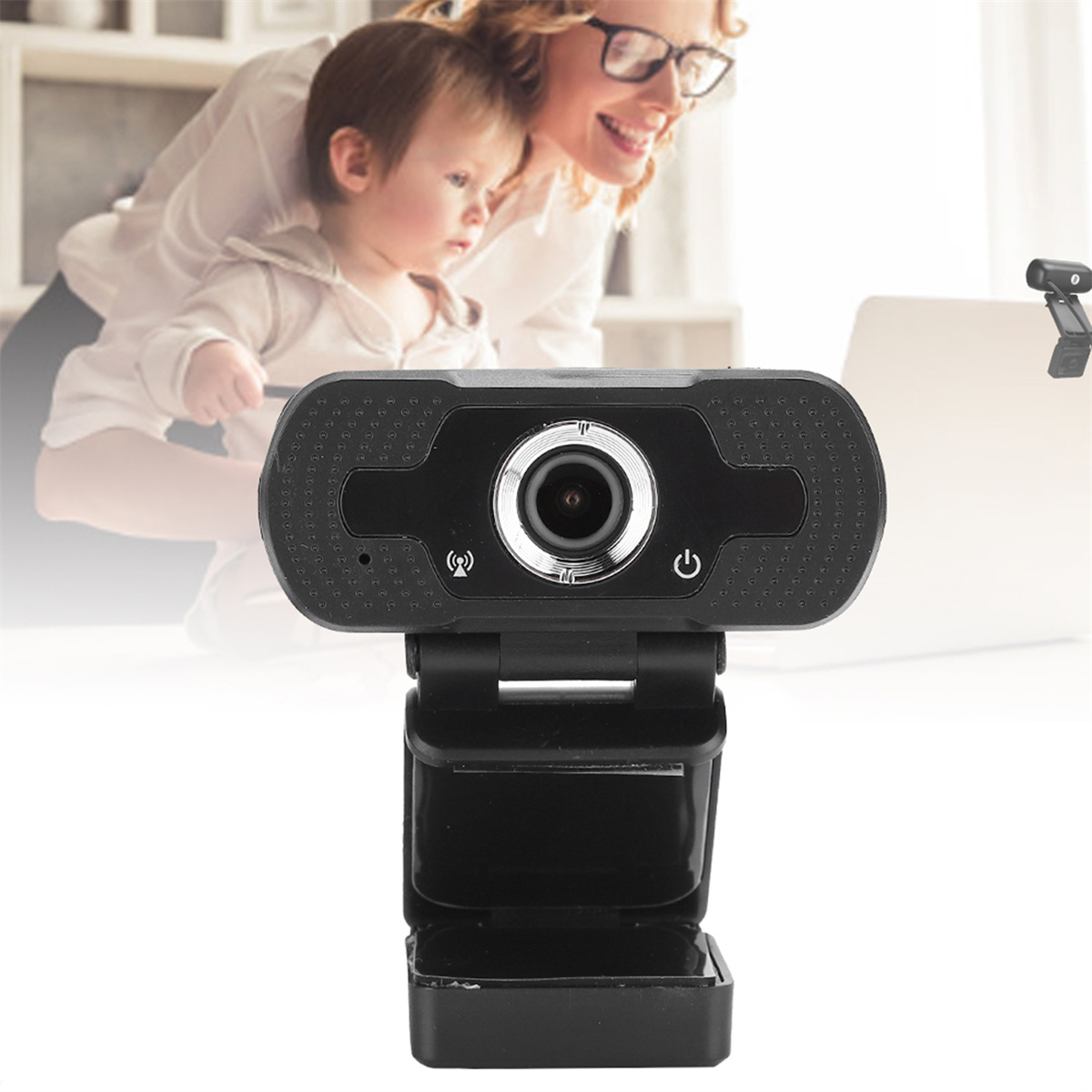 Eine schwarze Webcam ist auf einem Tisch montiert. Eine Frau und ein Baby sind im Hintergrund.