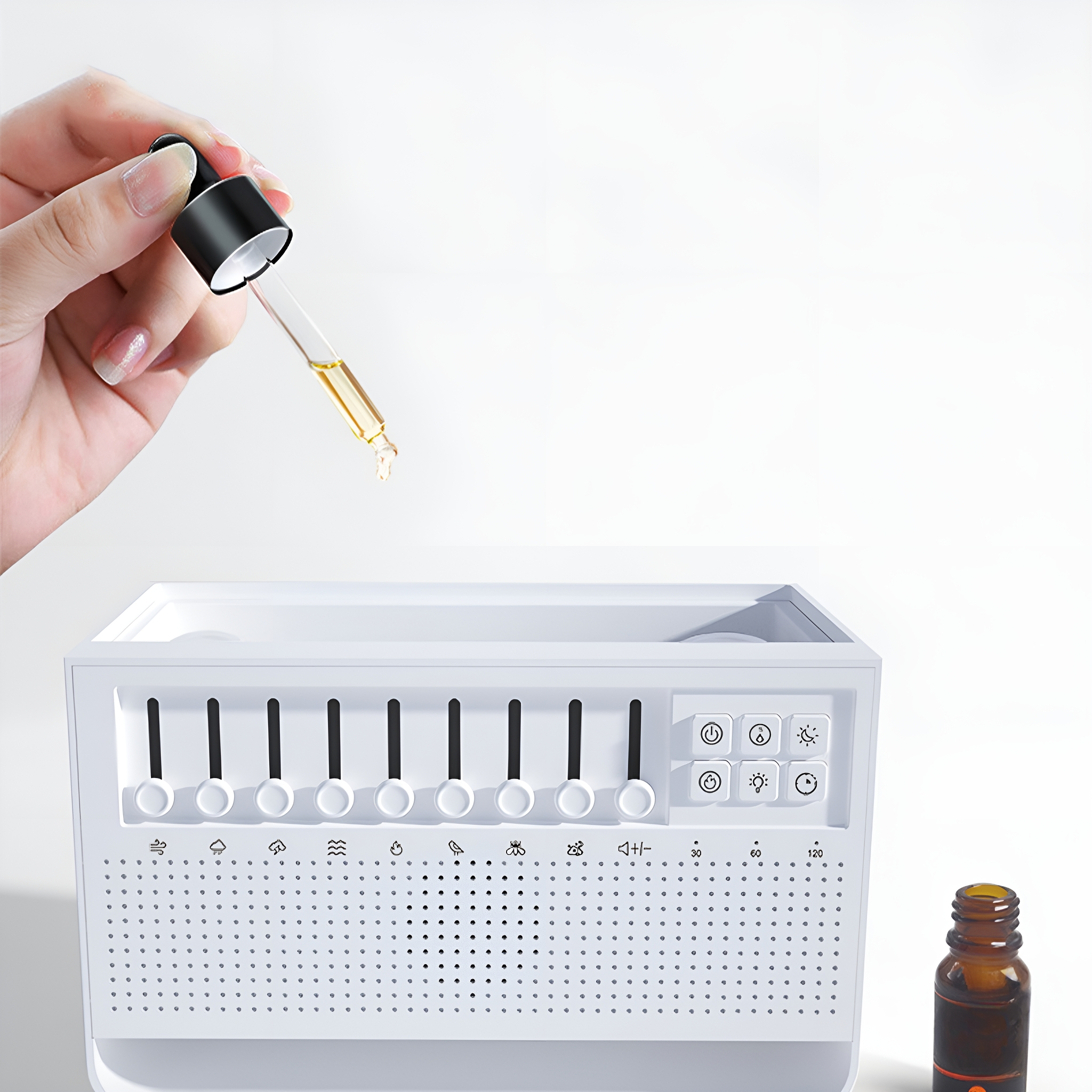 Eine Hand, die eine Pipette über einer weißen Geräuschmaschine mit einer Ölflasche hält.