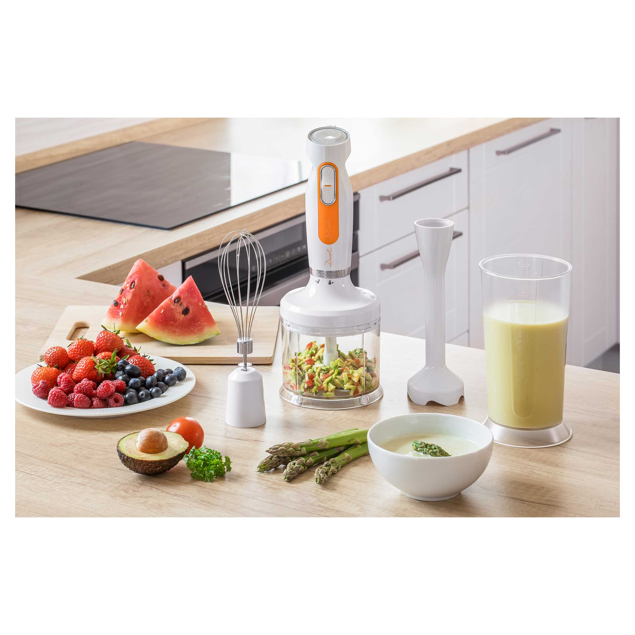 Un frullatore con ingredienti per un frullato su un tavolo di legno, con frutta, verdura e un bicchiere di frullato.