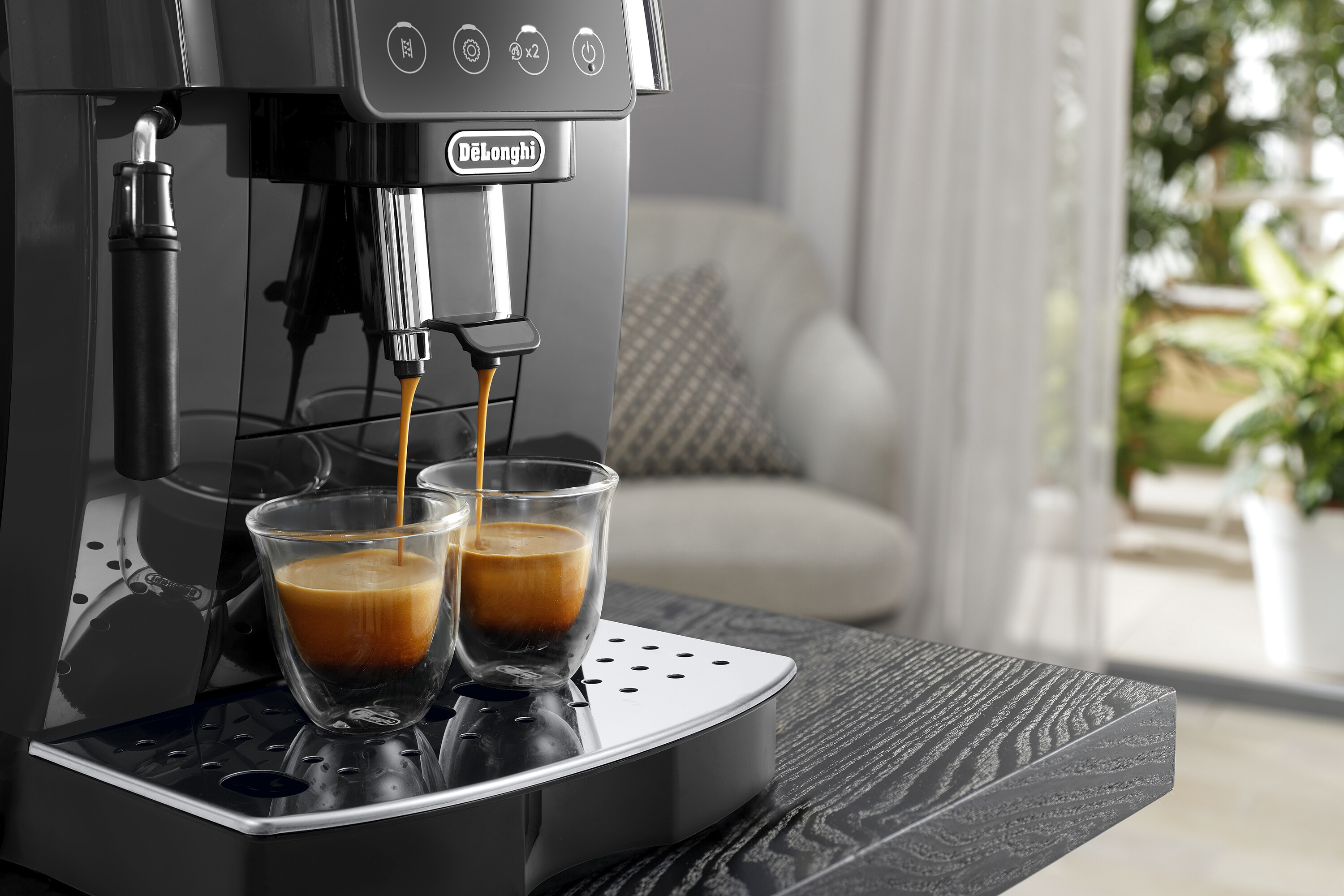 Macchina da caffè che versa espresso in due tazze di vetro trasparente su un vassoio.