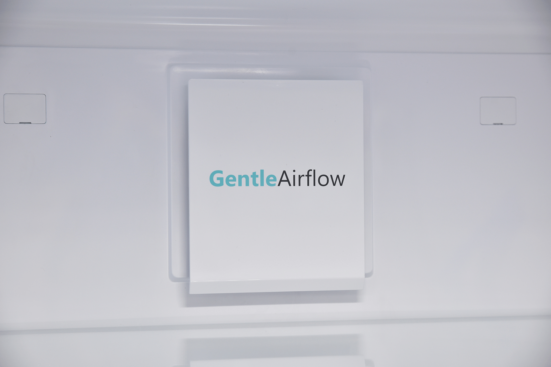 Białe wnętrze lodówki z napisem "GentleAirflow" na panelu.