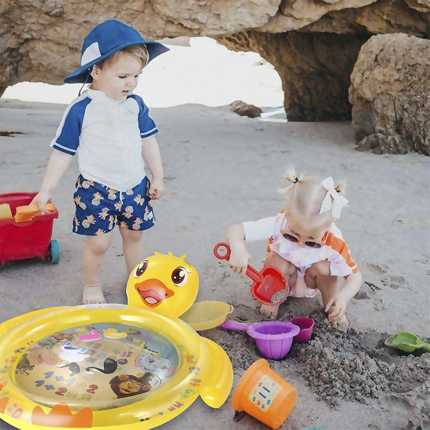 Due bambini che giocano su una spiaggia con una piccola piscina gonfiabile. Un bambino è in acqua.