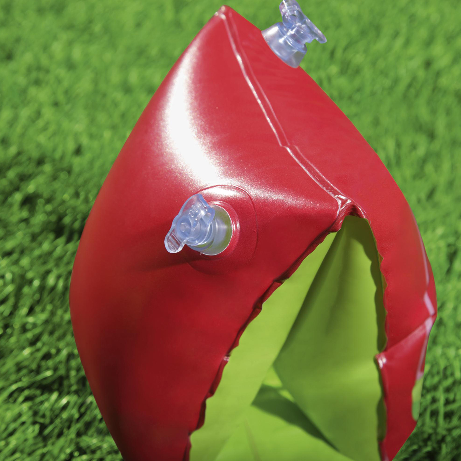 Un giocattolo acquatico gonfiabile rosso e verde su erba verde.