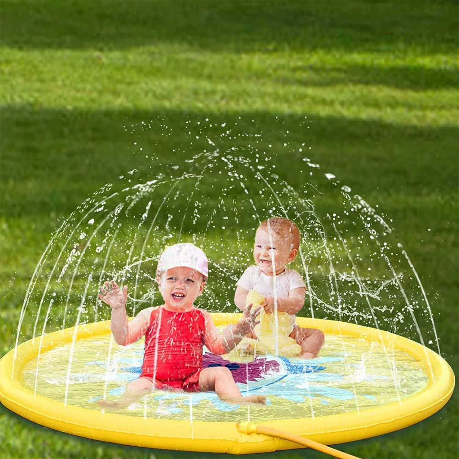 Dos bebés juegan en un parque acuático amarillo con fuentes de agua sobre césped verde.