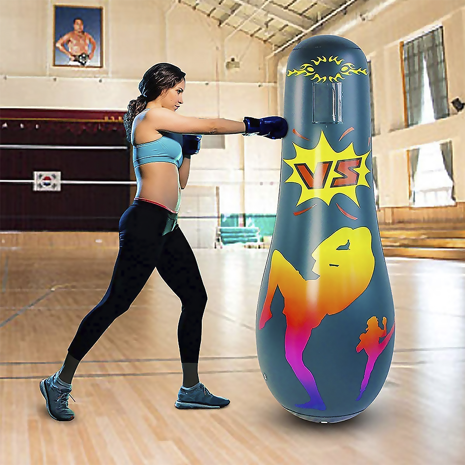 Una mujer está boxeando contra un saco de boxeo inflable alto con un diseño colorido.
