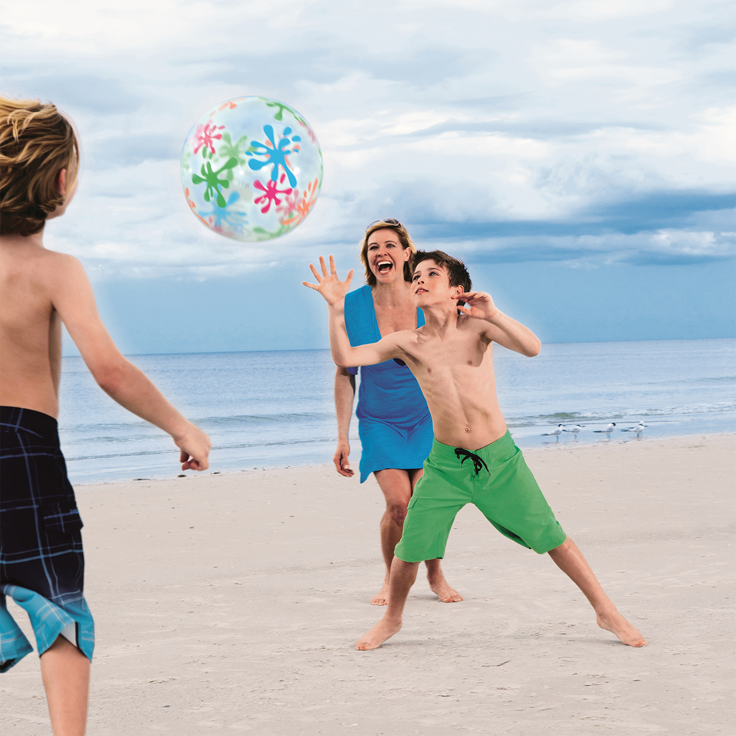 Tres personas jugando con una pelota de playa colorida en la playa.