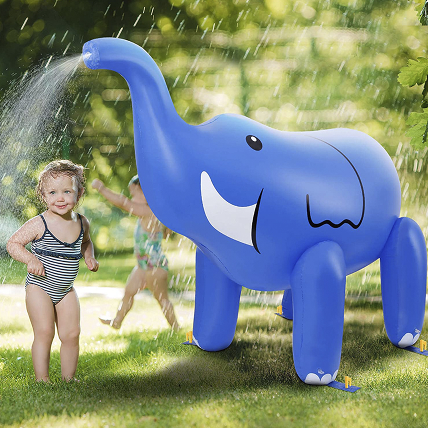 Una bambina in costume da bagno accanto a un gioco di spruzzatore a forma di elefante blu. Bambino sullo sfondo.