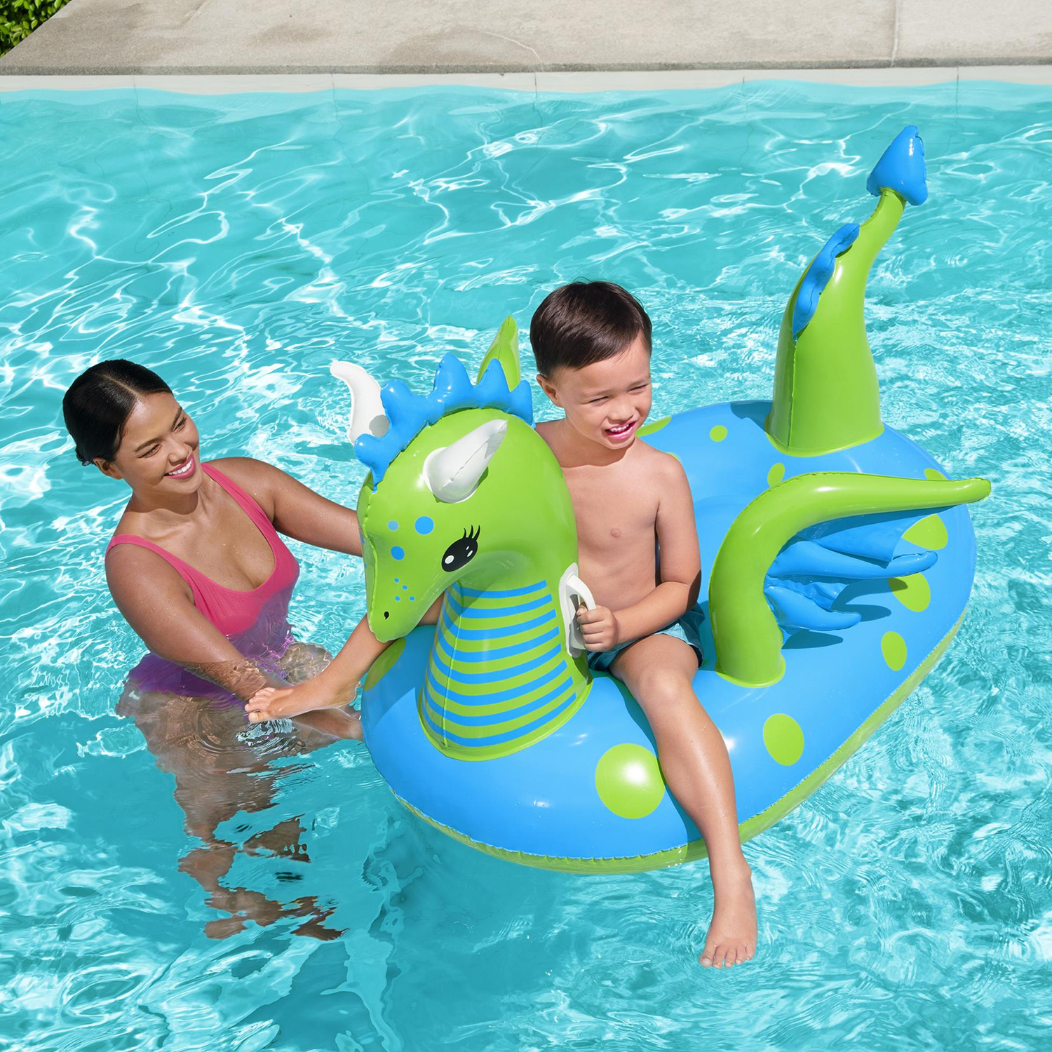 Una donna e un ragazzo su un galleggiante a forma di drago gonfiabile blu e verde in piscina.