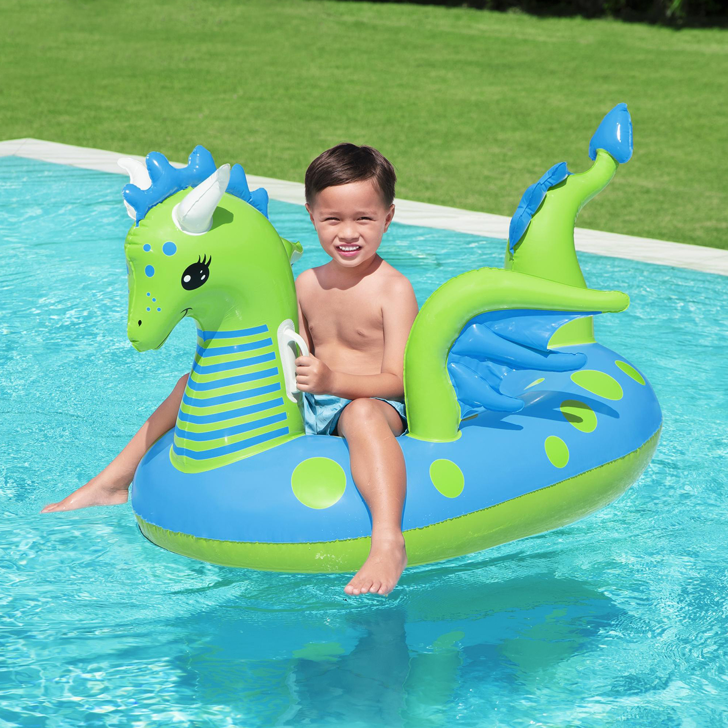 Un ragazzo è su un galleggiante a forma di drago verde e blu in piscina.