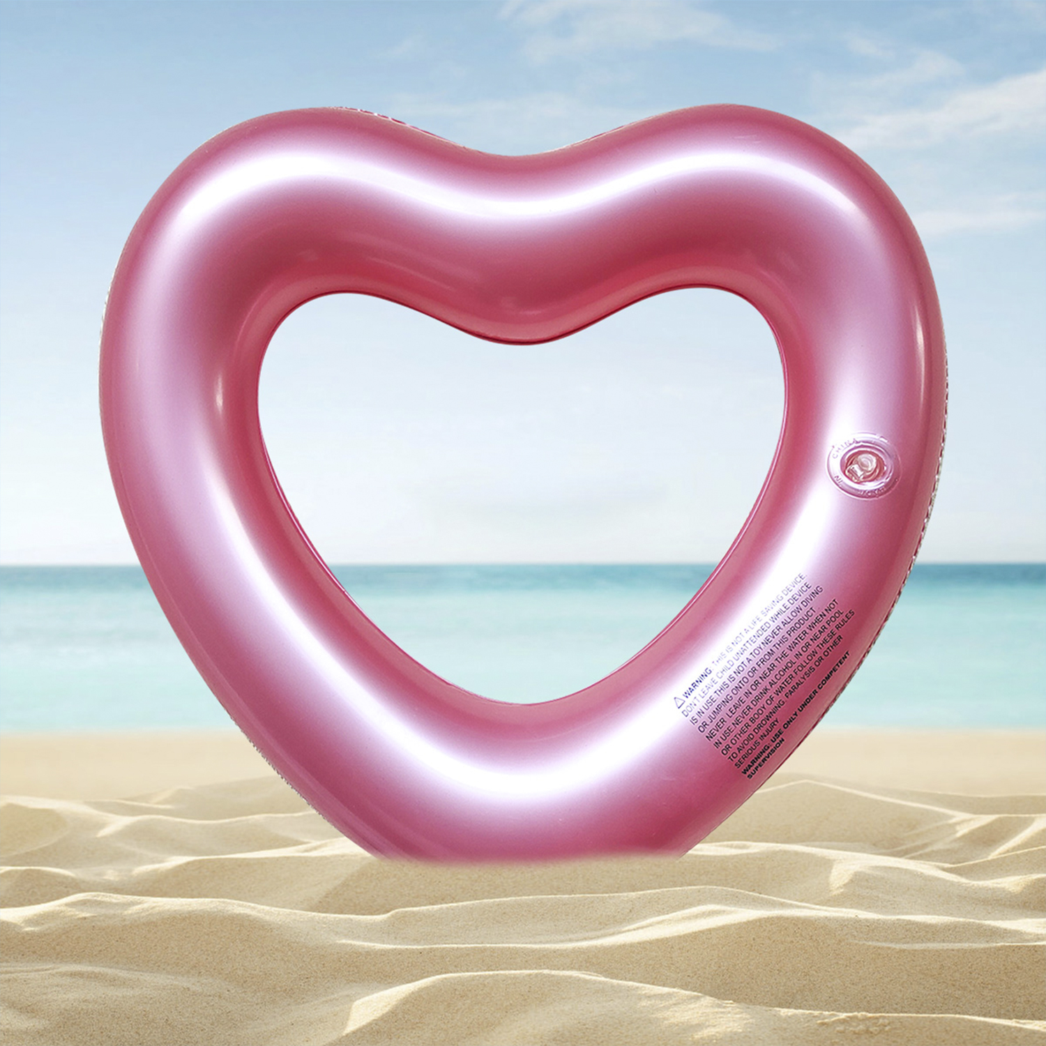 Flotador rosa en forma de corazón en la playa. Cielo azul. Arena en primer plano.