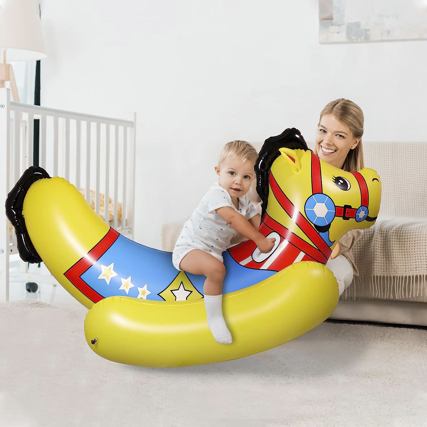 Un bebé en un caballo inflable amarillo, una mujer lo sostiene.