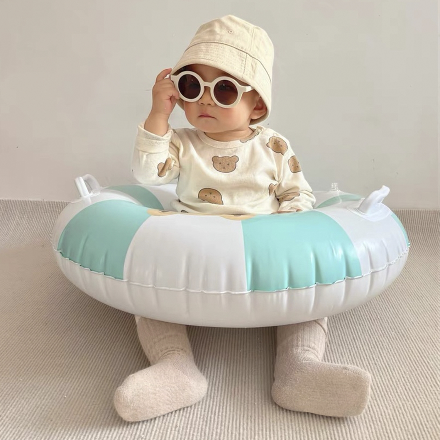 Bebé en un flotador, con gafas de sol y sombrero.