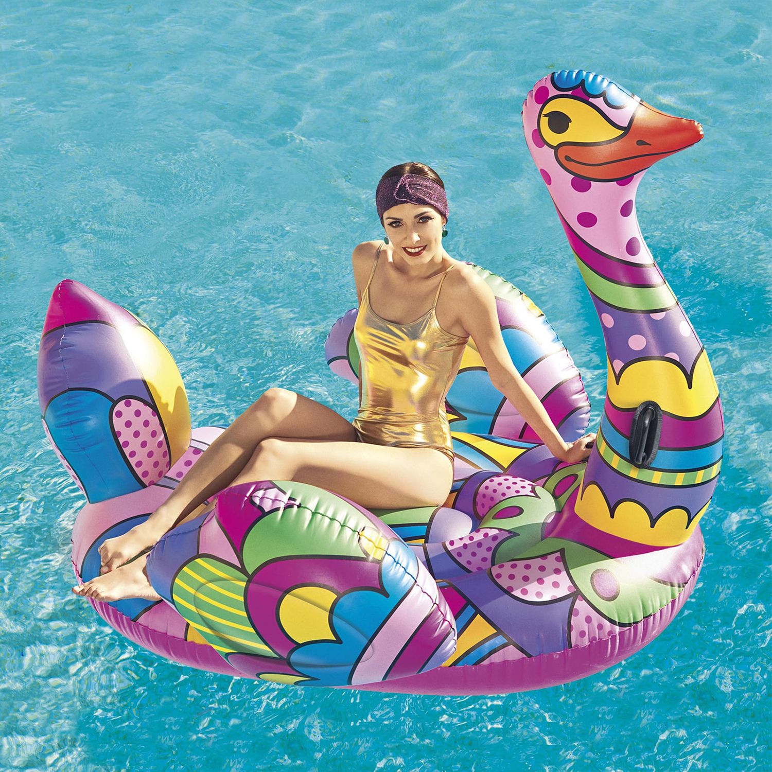Una donna in costume da bagno dorato su un galleggiante a forma di cigno colorato in una piscina.