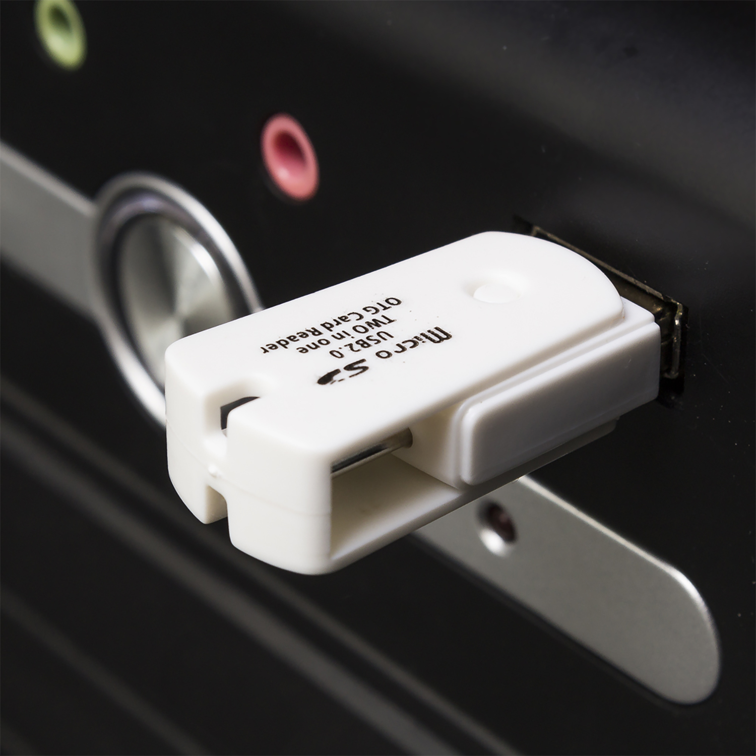 Un lector de tarjetas USB 2.0 OTG blanco enchufado a una computadora negra.