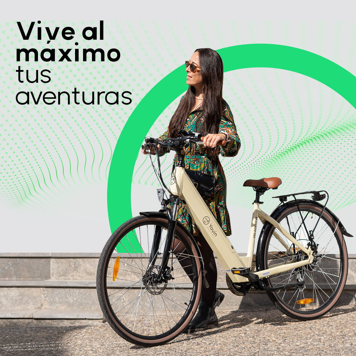 Kobieta na kremowym rowerze elektrycznym, jadąca po kamiennej ścieżce. Zielony wzór w tle.