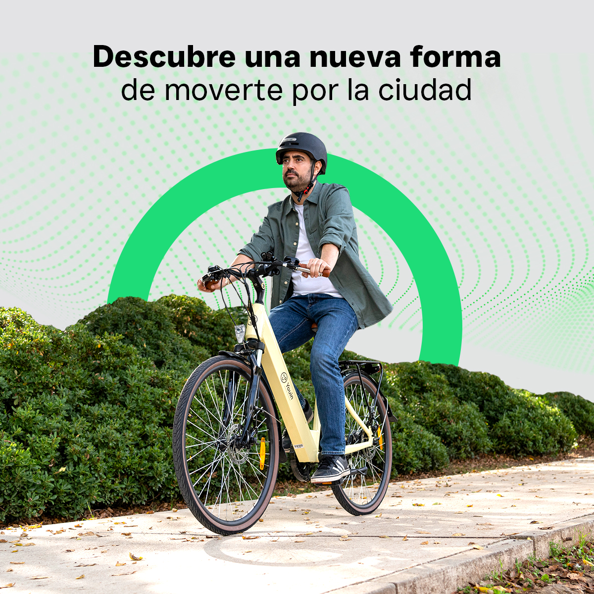 Mężczyzna jadący żółtym rowerem elektrycznym po utwardzonej ścieżce obok zielonych krzewów.