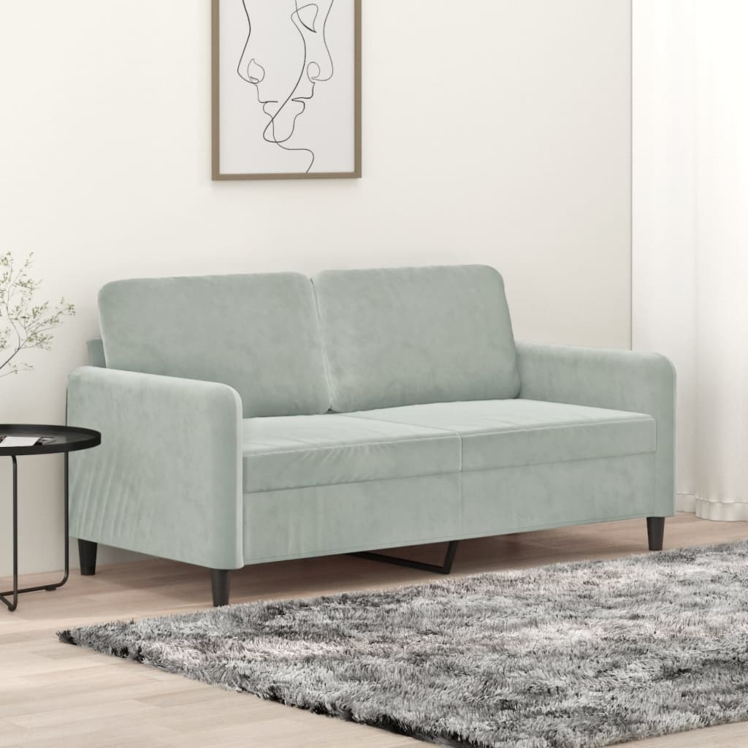 Ein hellgrünes Sofa mit einem Gemälde und einem Teppich in einer Wohnung.