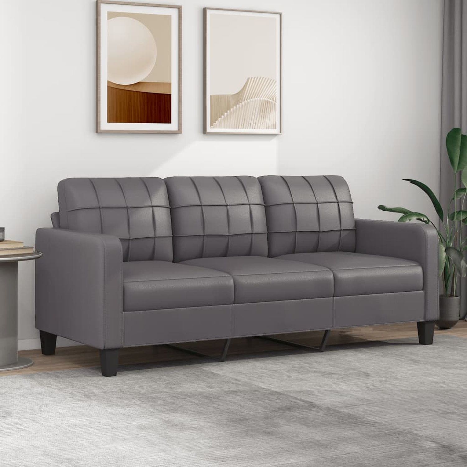 Ein graues Sofa mit Gittermuster. Zwei gerahmte Bilder hängen darüber. Das Sofa hat schwarze Beine.