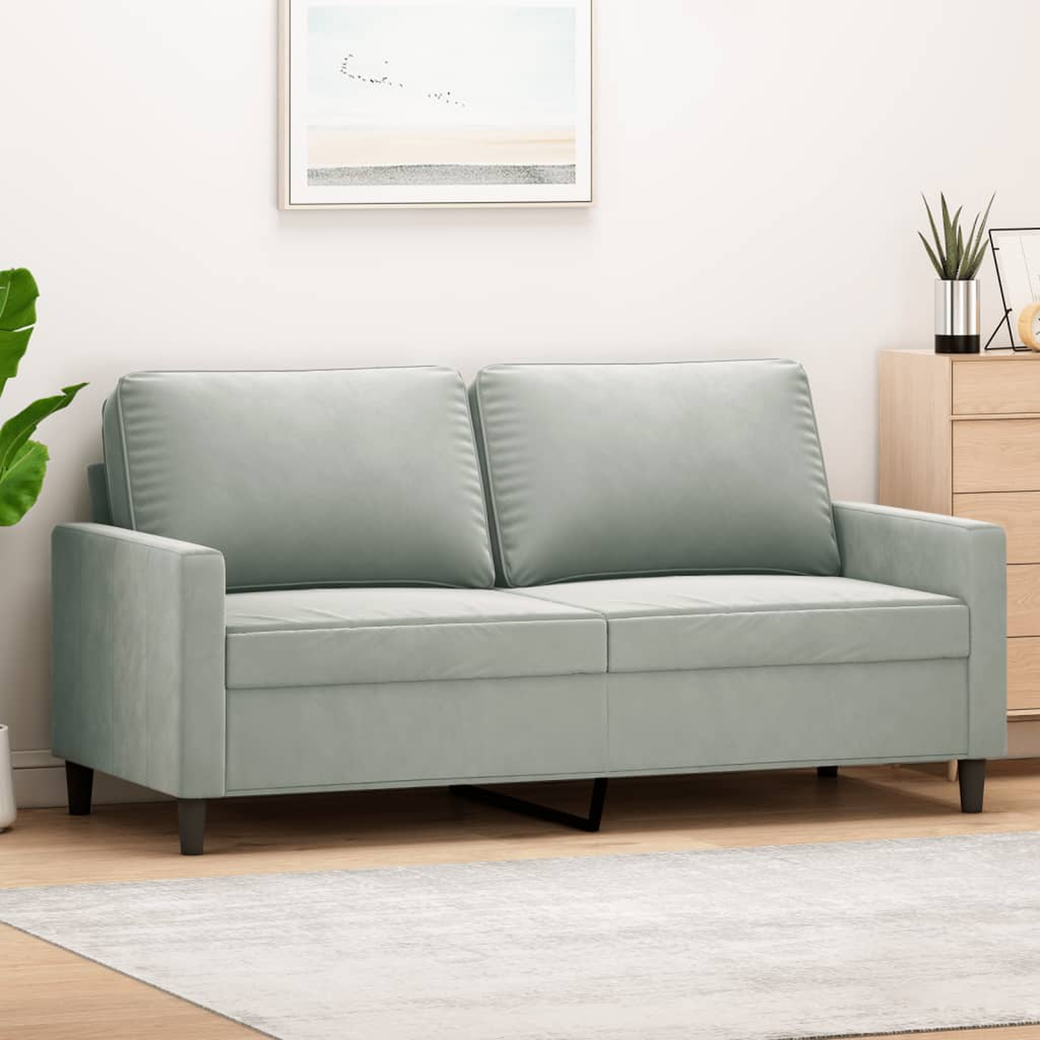 Ein hellgraues Sofa in einem Raum mit einem Gemälde und einem Holzschrank. Es gibt einen Teppich.