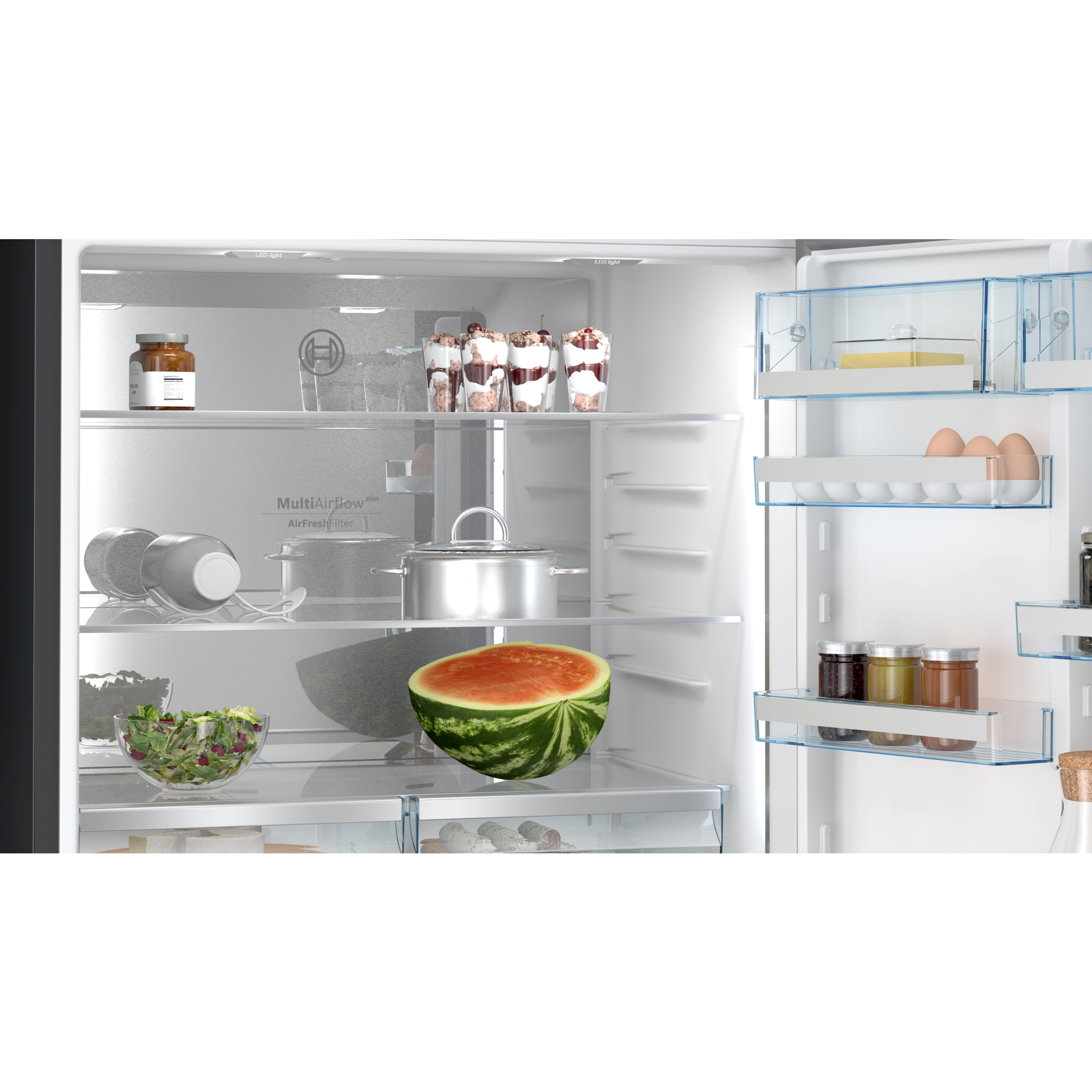 Interior de un refrigerador con varios alimentos: sandía, ensalada, frascos, huevos y postres.