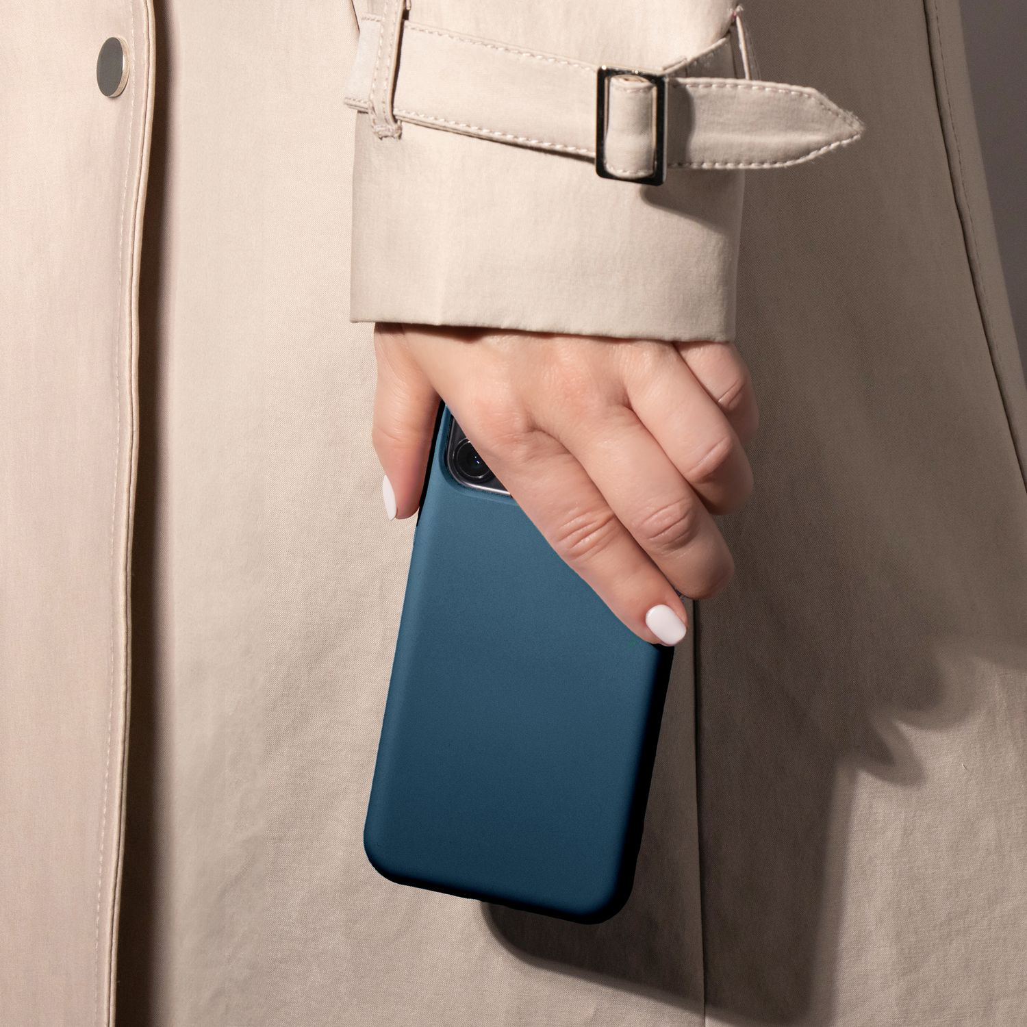Eine Person hält eine blaue Handyhülle neben einem beigefarbenen Trenchcoat.