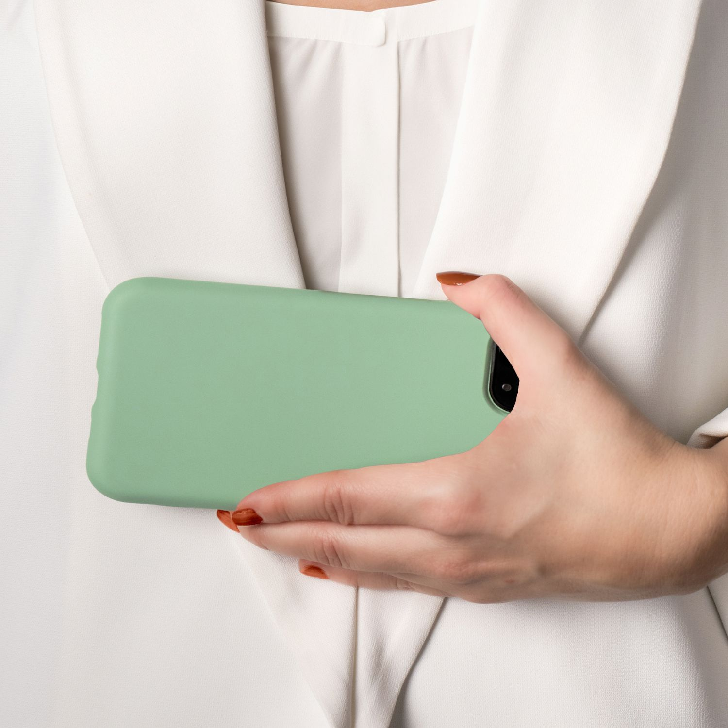 Eine Hand hält eine mintgrüne Handyhülle, ein weißes Hemd im Hintergrund.