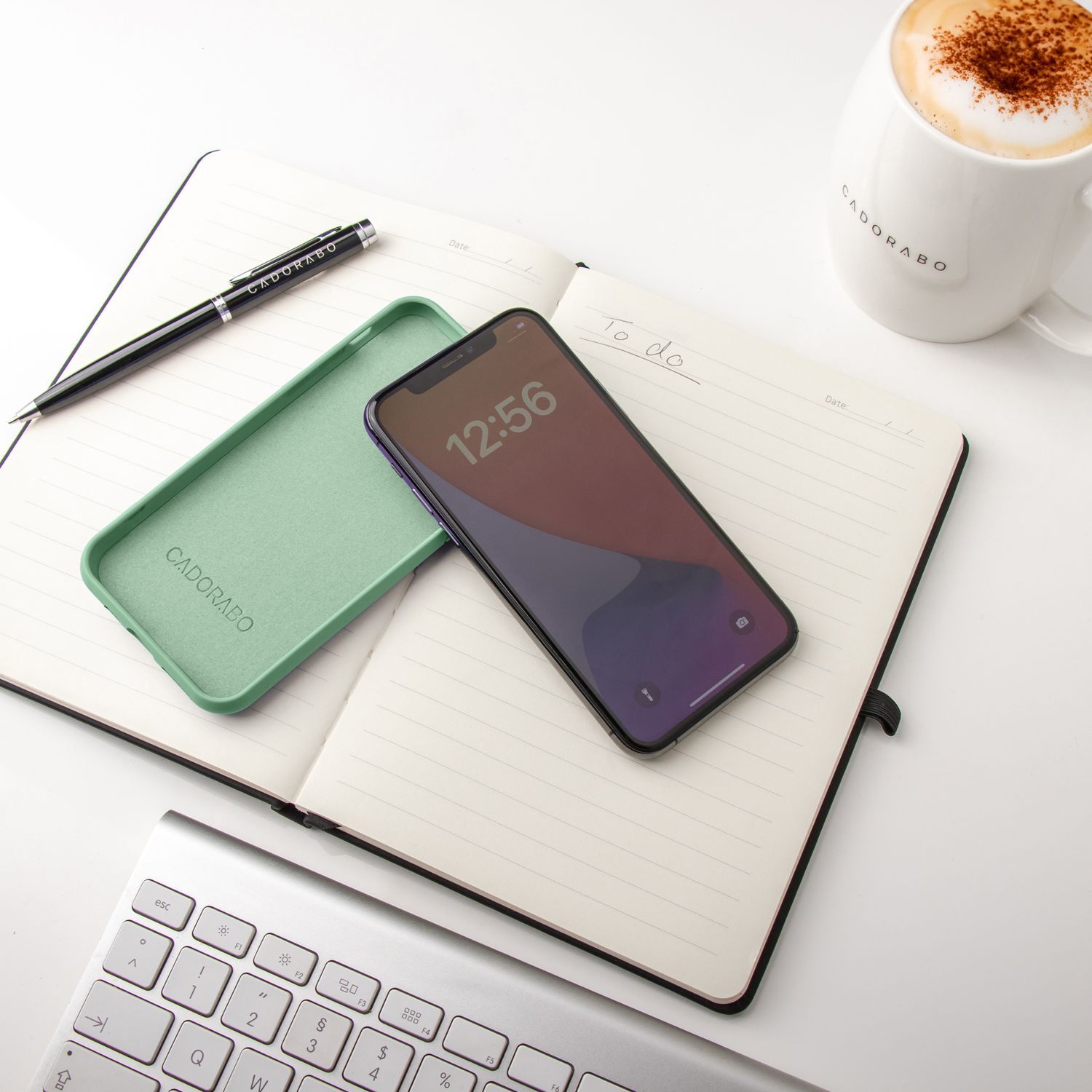 Ein Schreibtisch mit Telefon, Handyhülle, Stift, Notizbuch und Tasse.